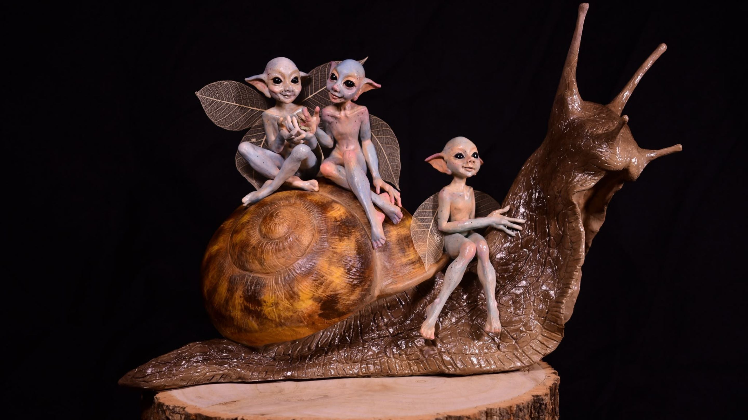 Orange sculptures of three mischievous looking Cornish pixies