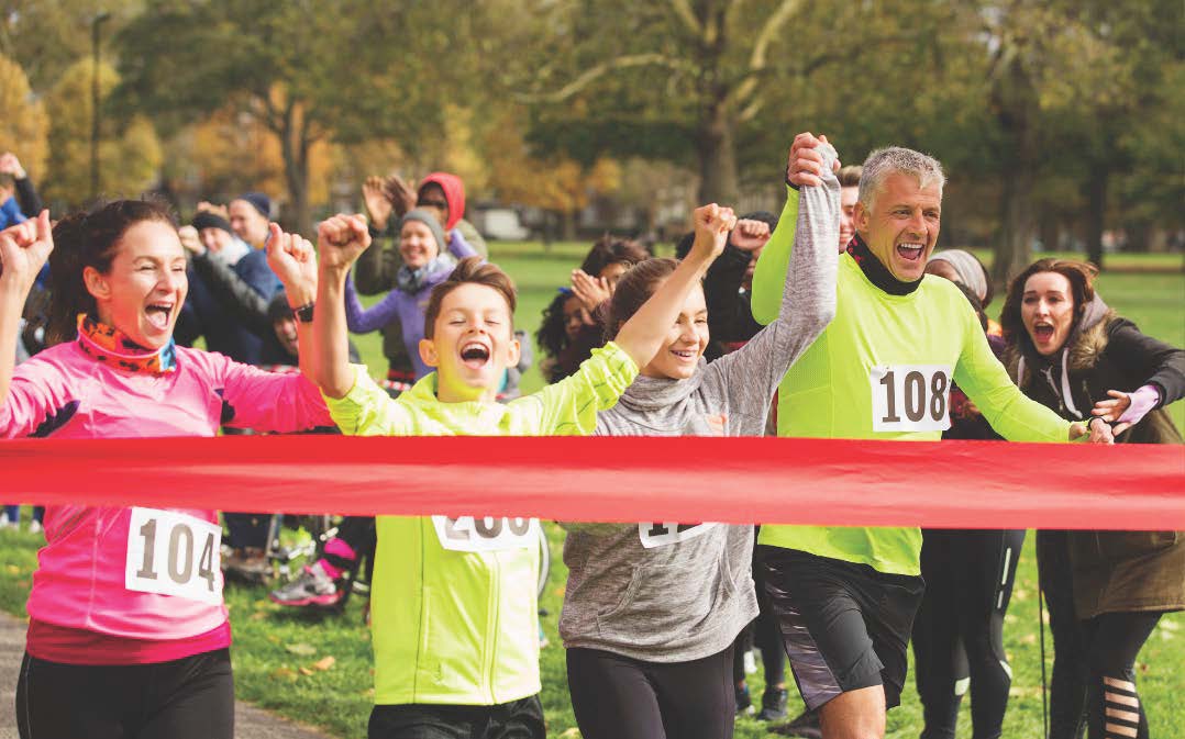The image shows people in bright colours taking part in a race