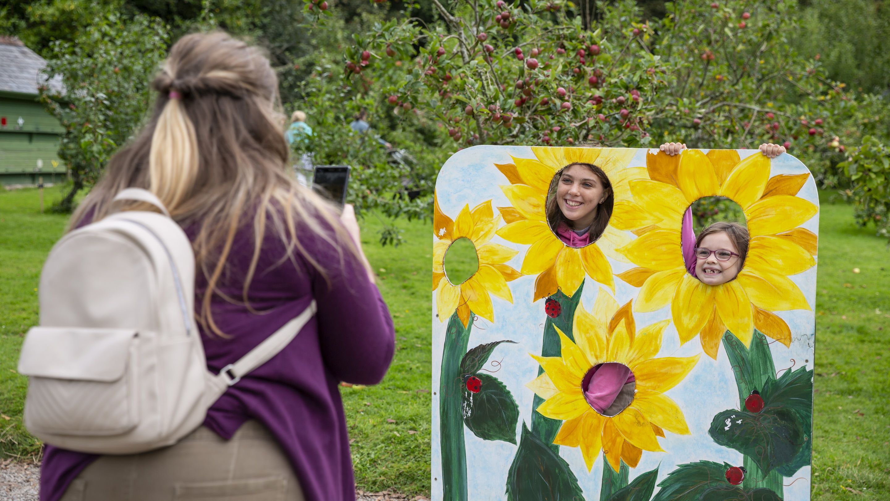 Adult taking photo of children behind a flowery selfie station