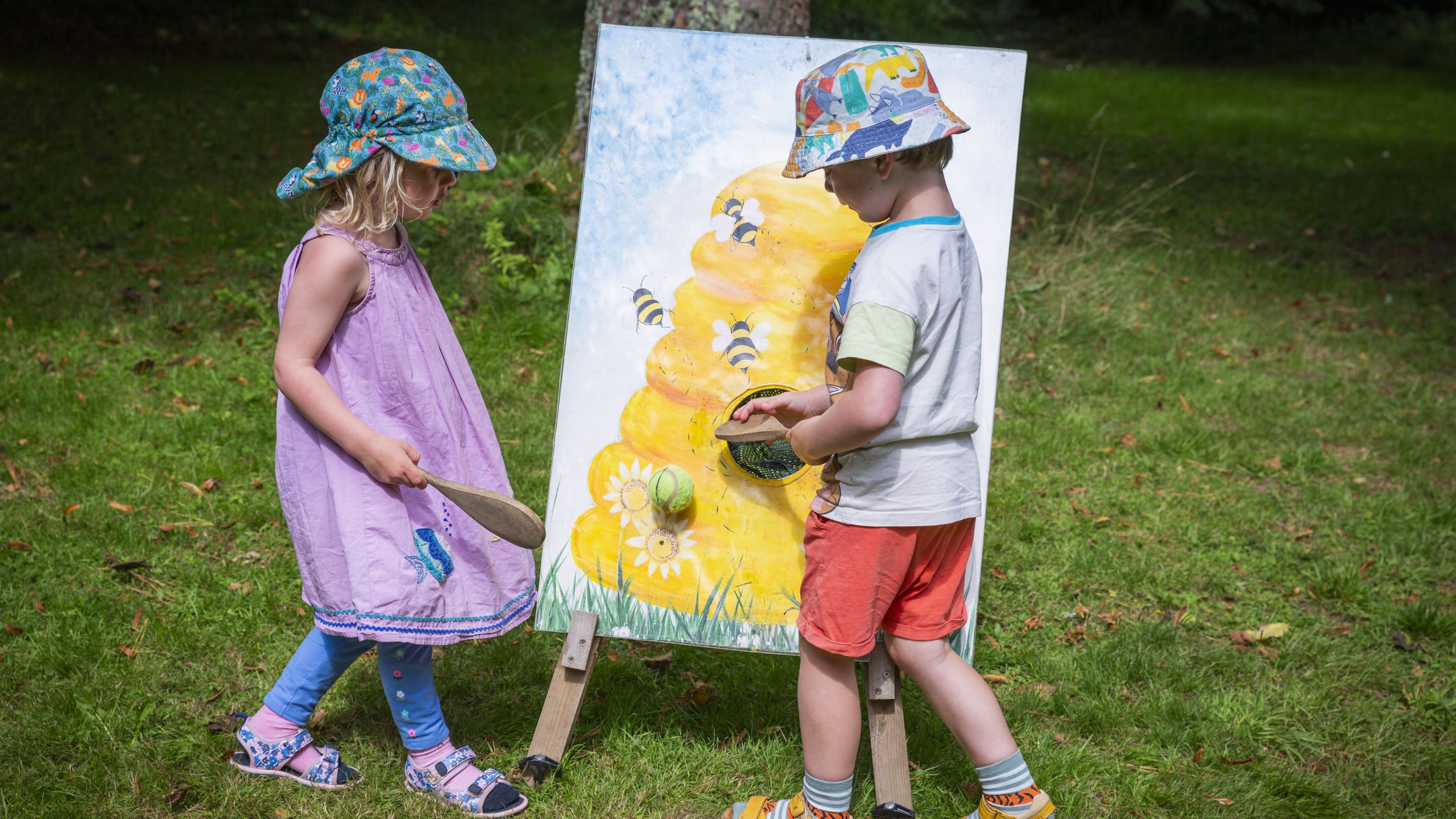 Two children playing in front of a colourful board