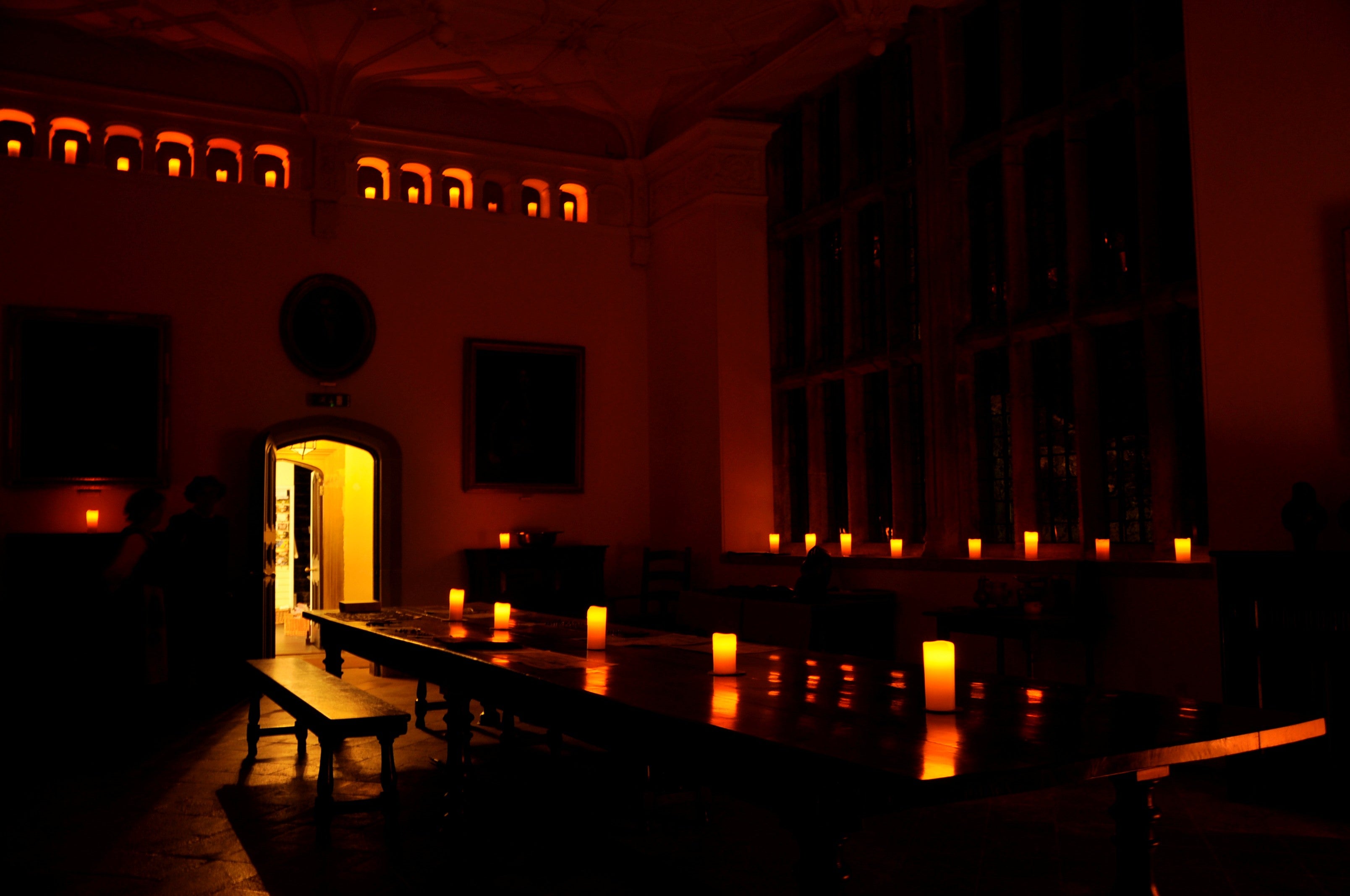 An image of the Great Hall at Trerice in darkness, lit with candles