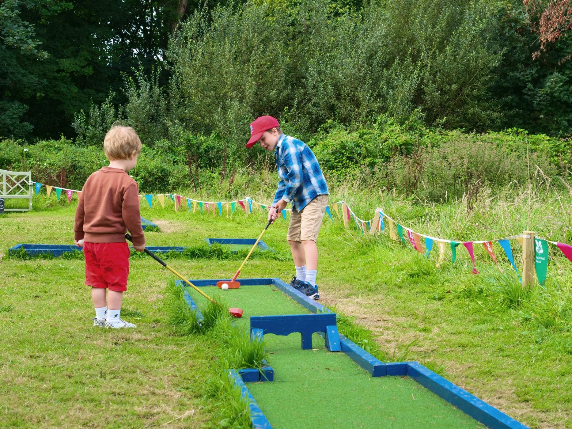 Two children playing mini golf during Summer of Play at Trerice, Cornwall.