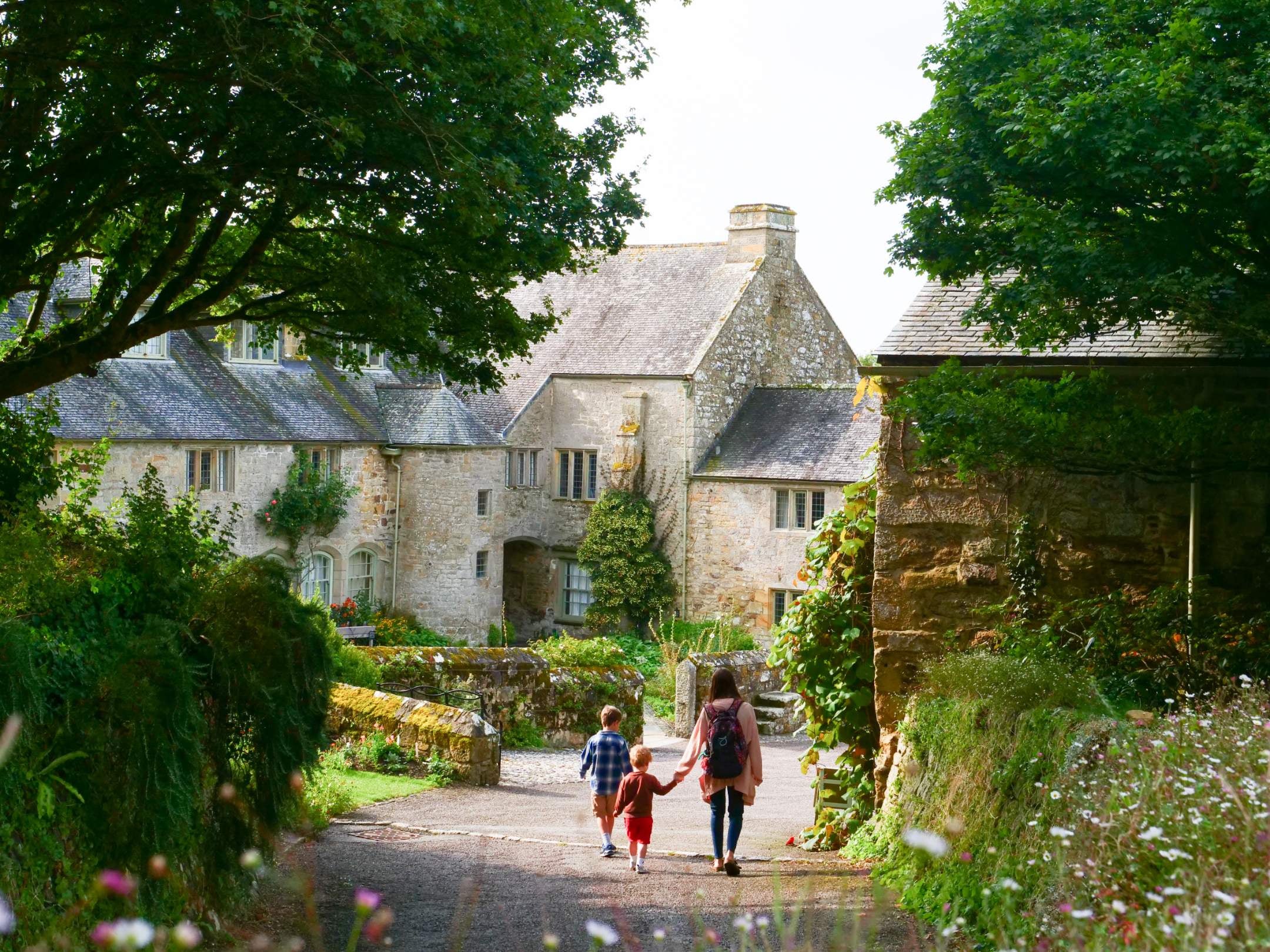 A family walking through Trerice in summer, with the rear court in background, Trerice, Cornwall