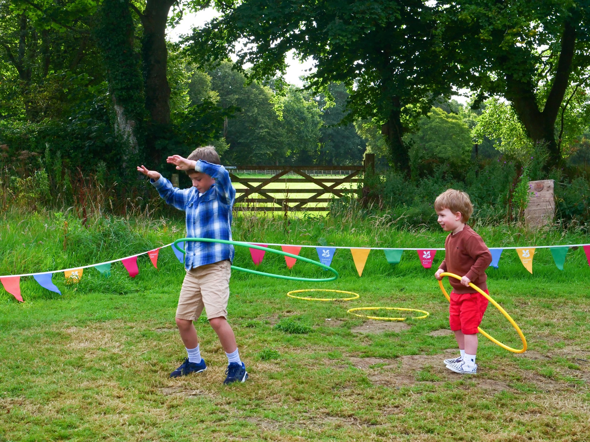 An image of two children hula hooping in the field at Trerice as part of their Summer of Play activities