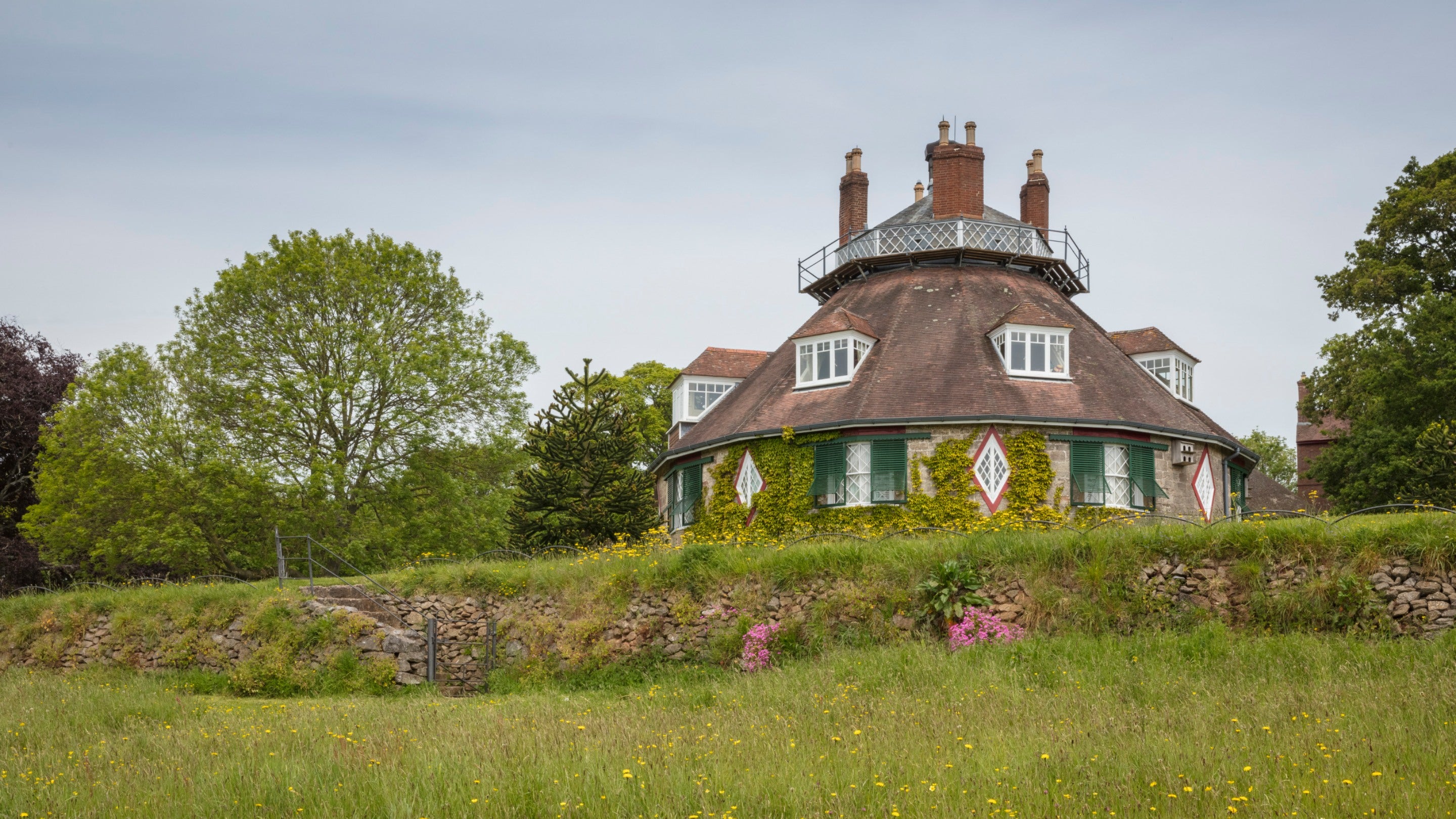View of the octagonal house at A la Ronde with trees and flowering meadow