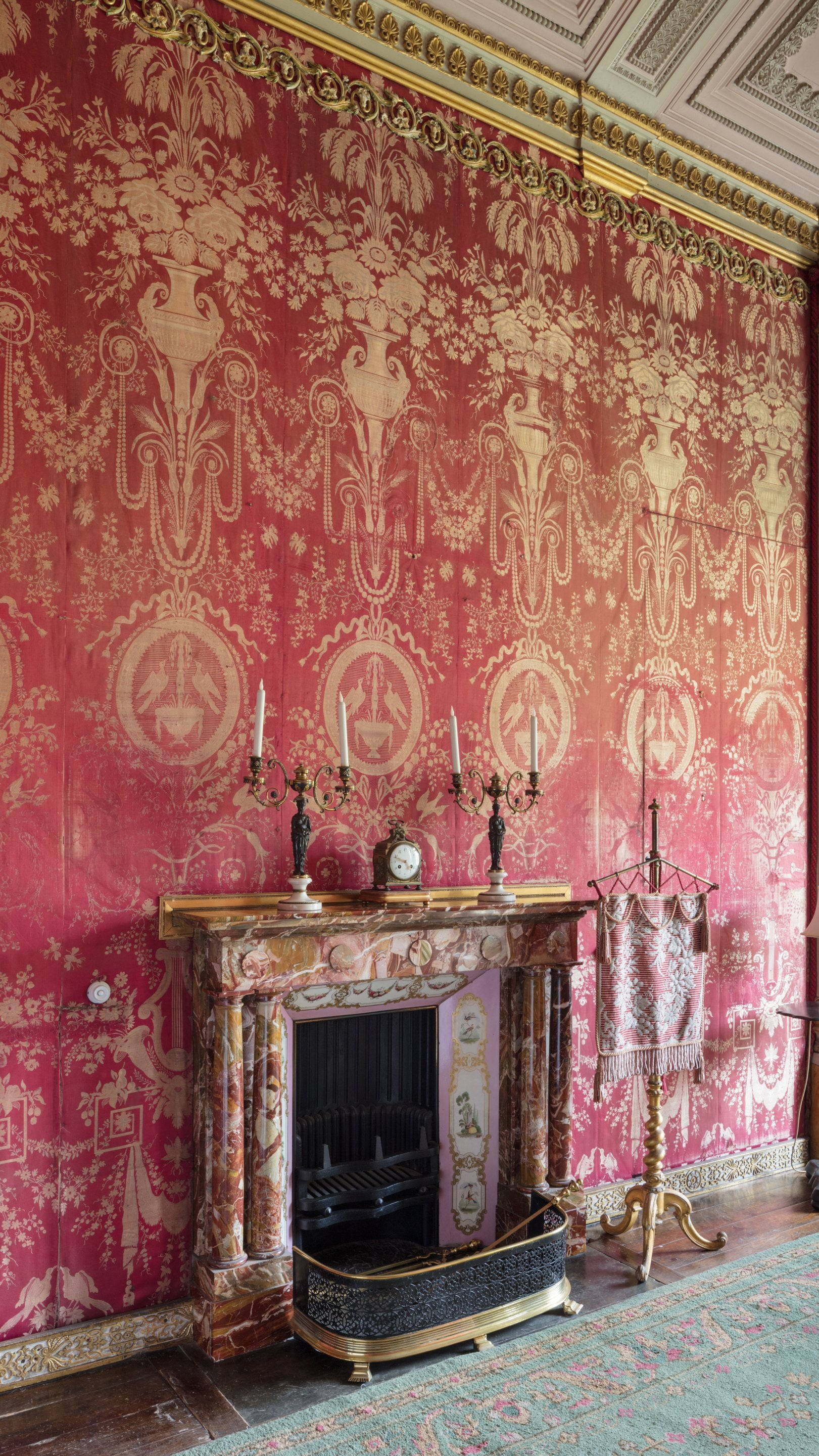 View of the Boudoir at Arlington Court and the National Trust Carriage Museum, Devon, showing the fireplace and the rare crimson and gold silk damask hangings.