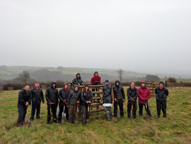 A group of rangers dress in wet weather gear, posing for a photo in a field
