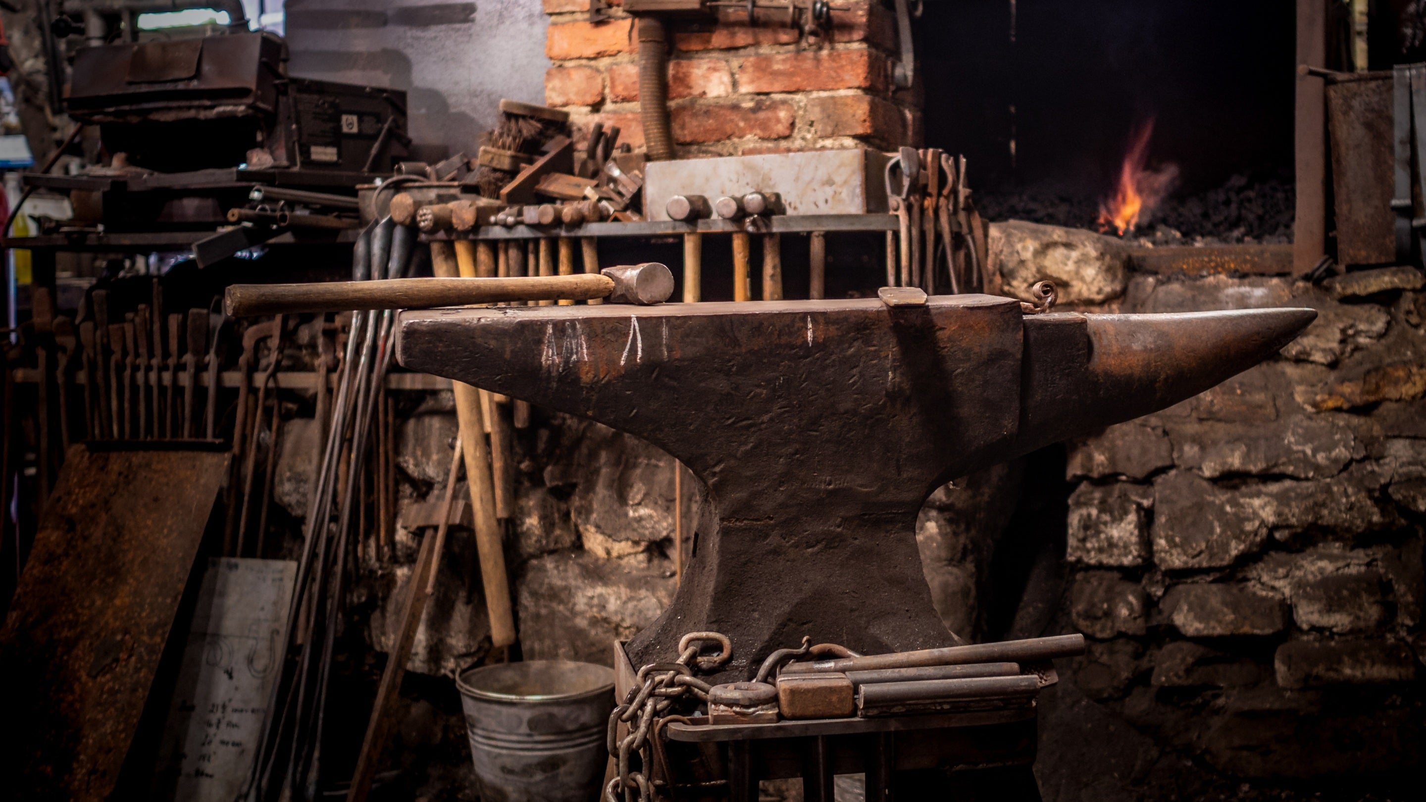 view of an anvil inside a forge with fire and blacksmith tools