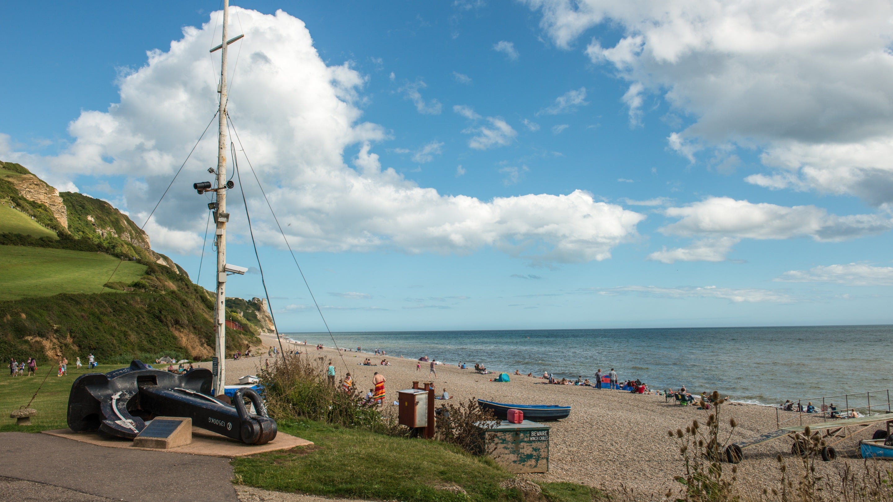 View of visitors in the distance enjoying the beach at Branscombe, Devon on a sunny day