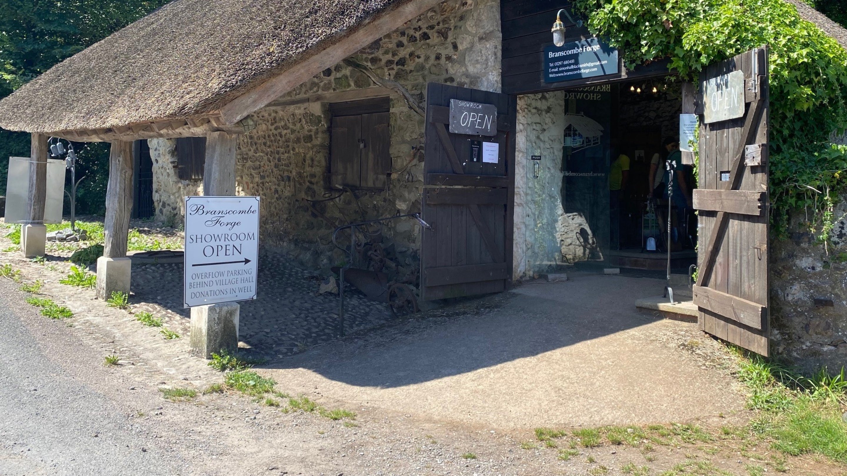 Concrete ramp leading into a doorway entrance to a thatched forge building