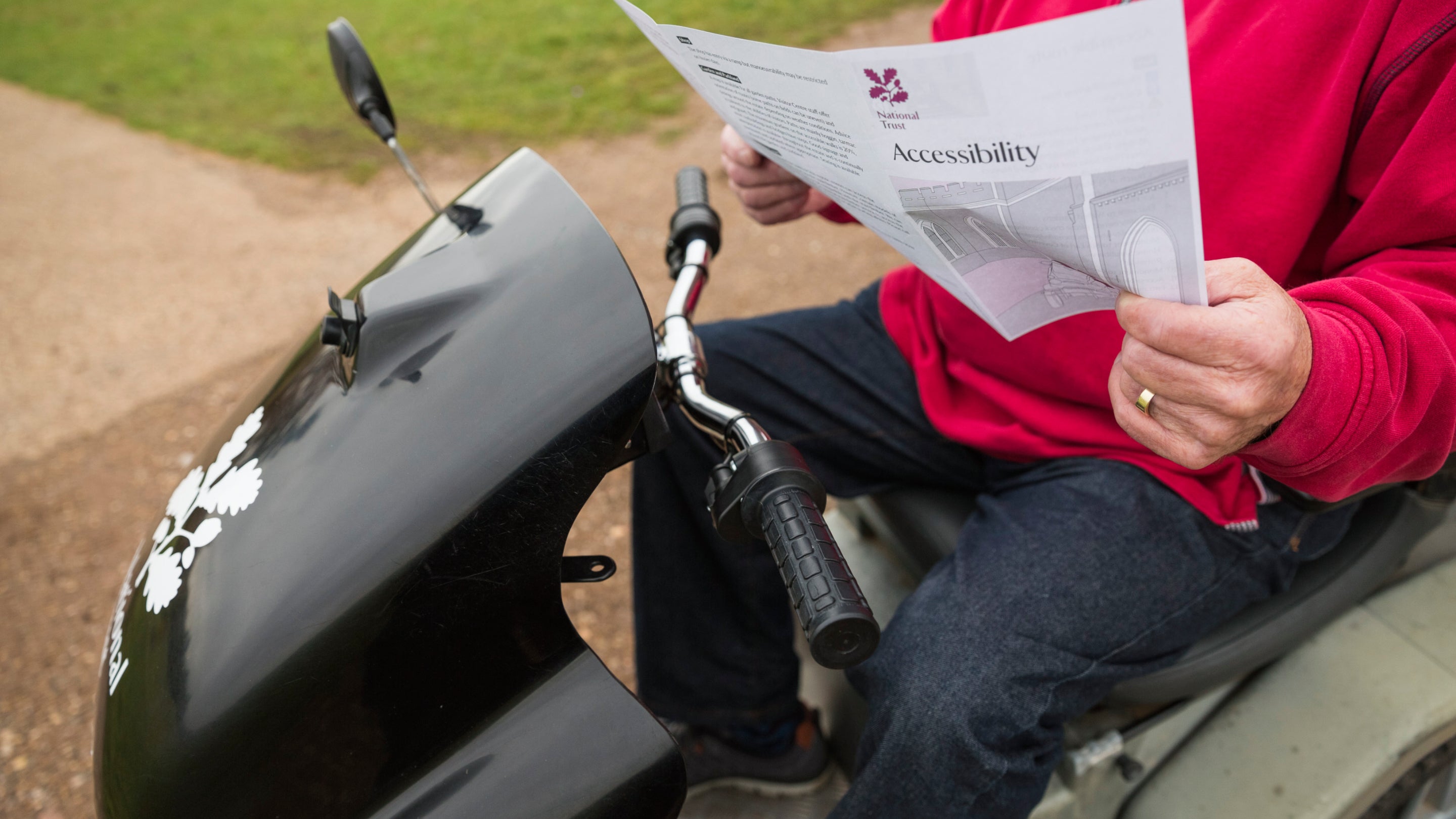 A close up of a visitor on the Tramper reading an accessibility pamphlet