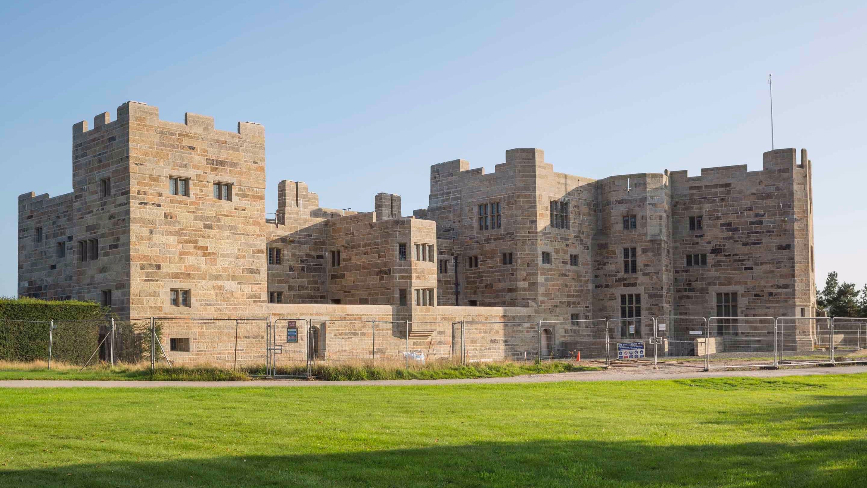 Outside the front of Castle Drogo, surrounded by fencing after years of conservation work, in Devon