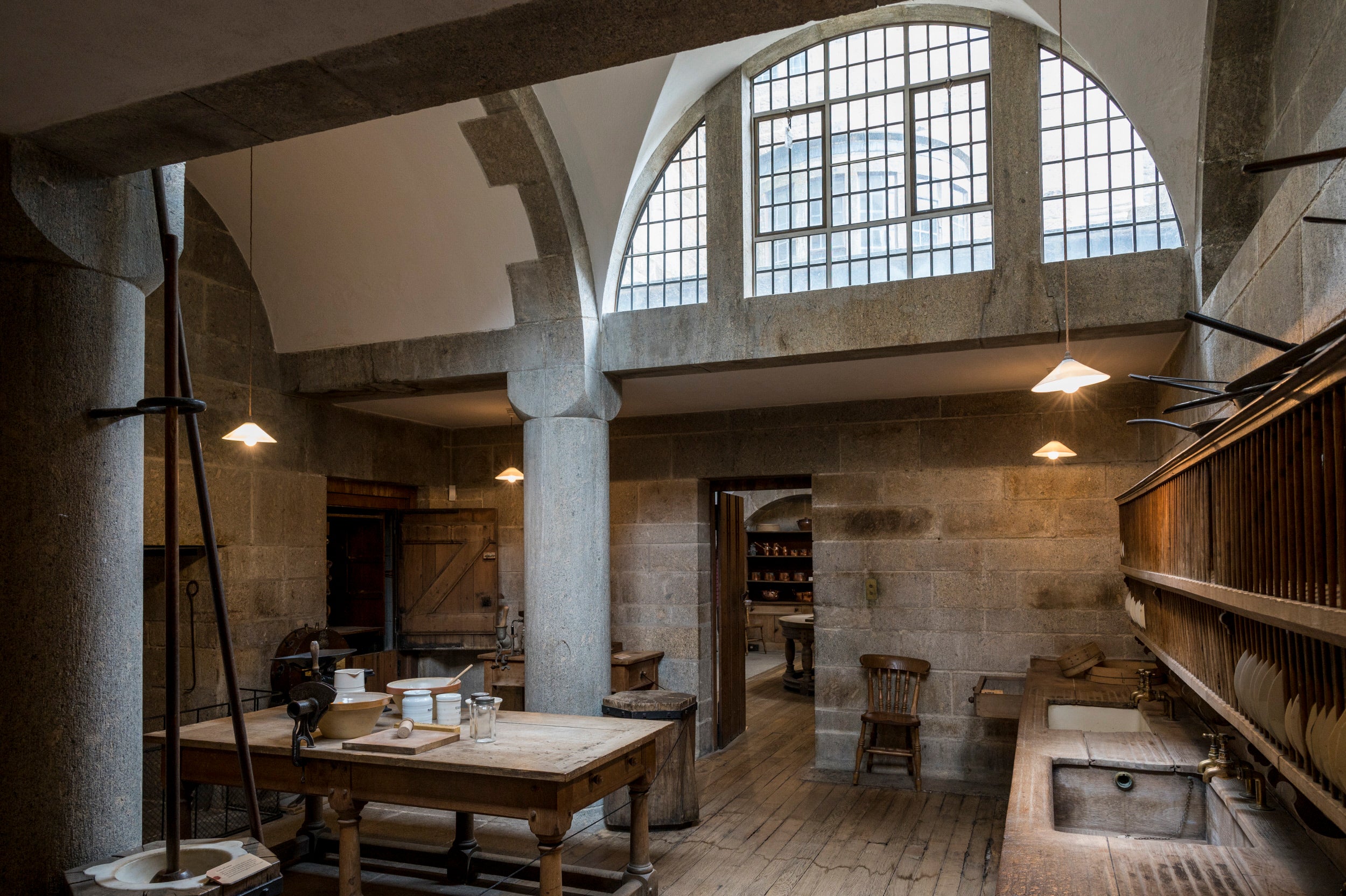 Large half circle window in a granite room with tables and a wooden sink. There are stone pillars around the room