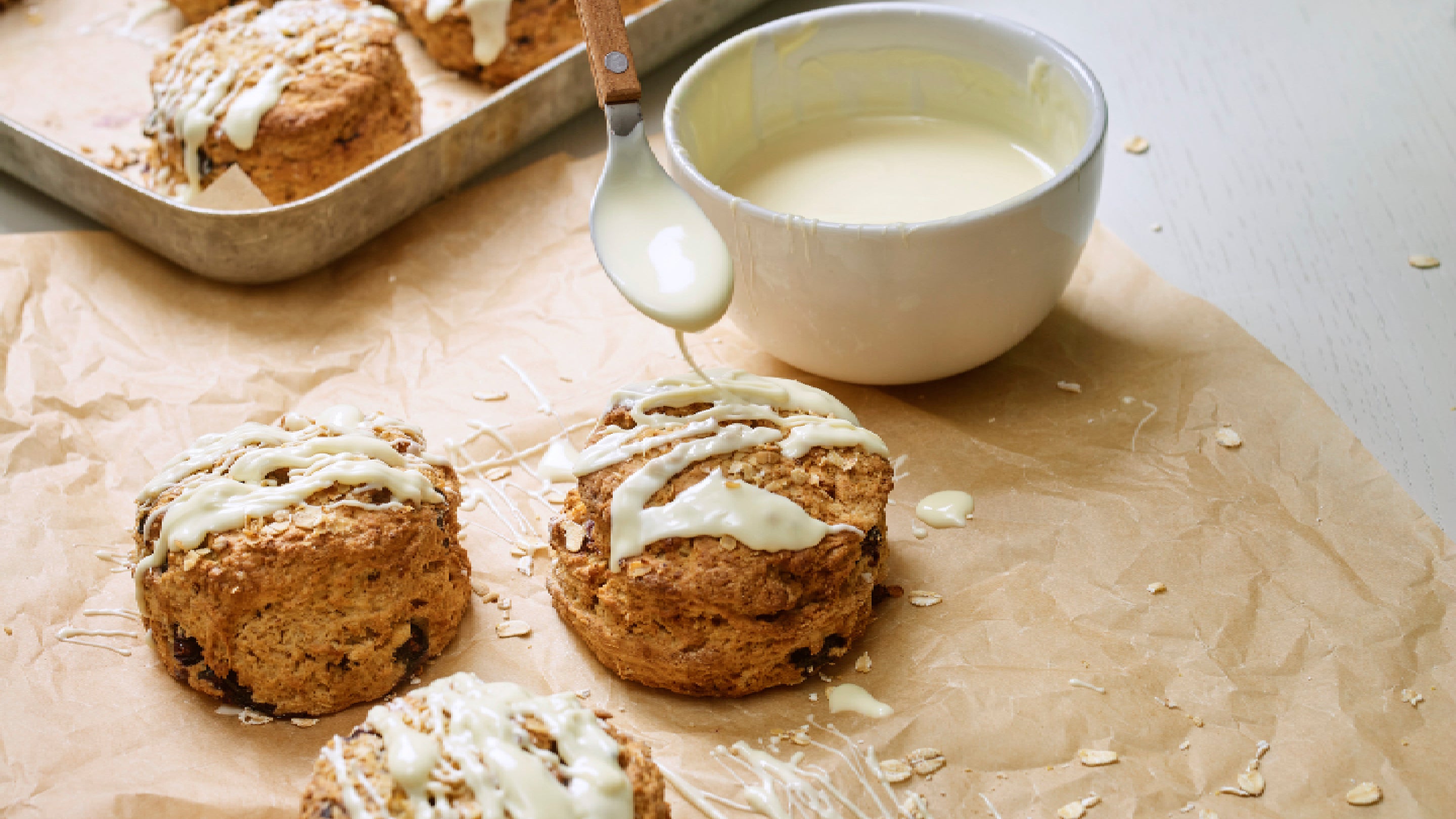 A selection of the Blueberry and Oats scones being prepared with a white chocolate drizzle.