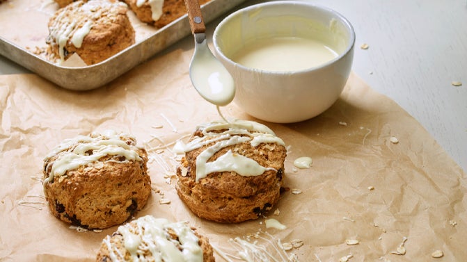 A selection of the Blueberry and Oats scones being prepared with a white chocolate drizzle.