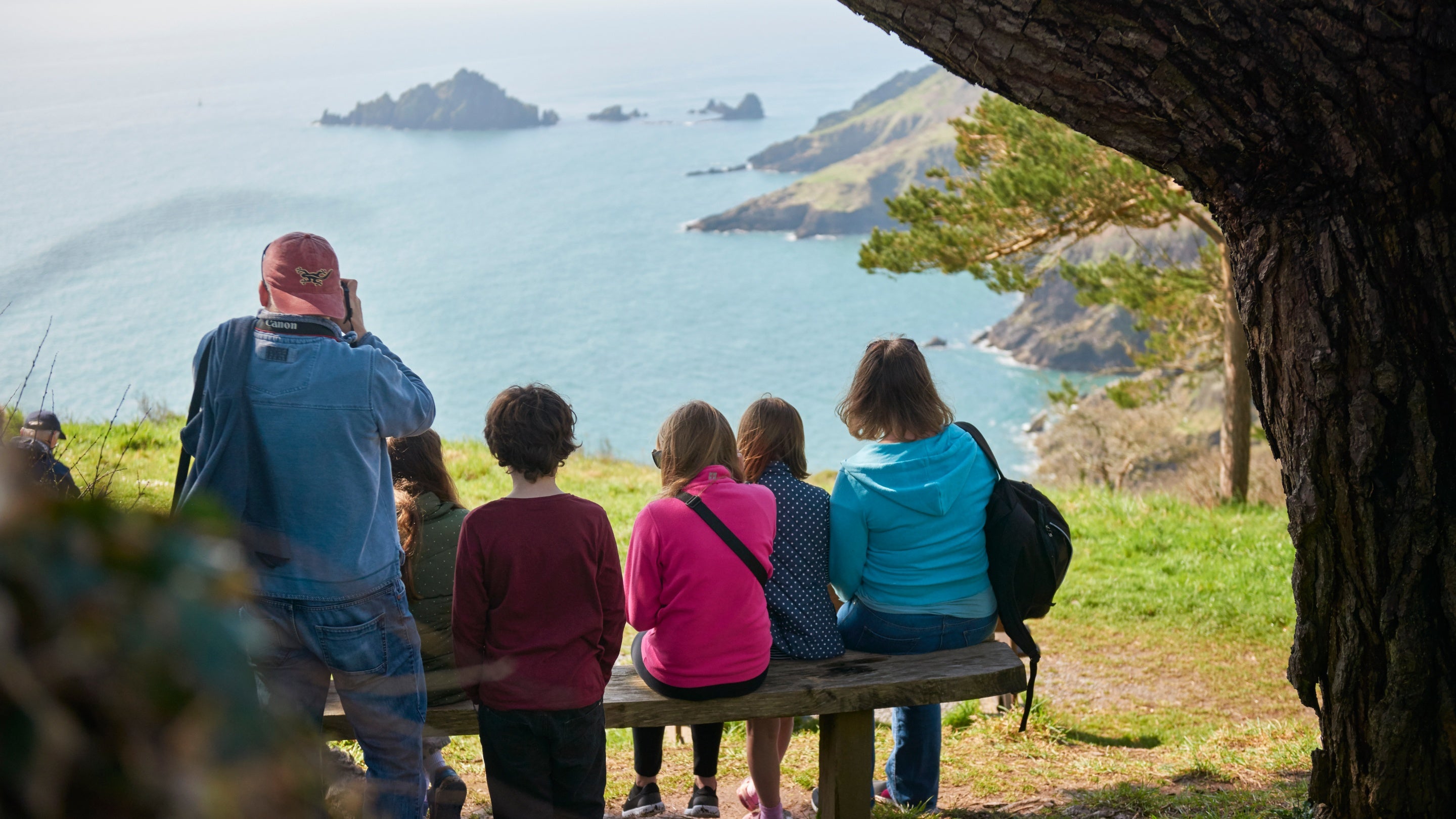 Visitors enjoying the view of Pudcombe Cove from the South West Coast Path at Coleton Fishacre, South Devon