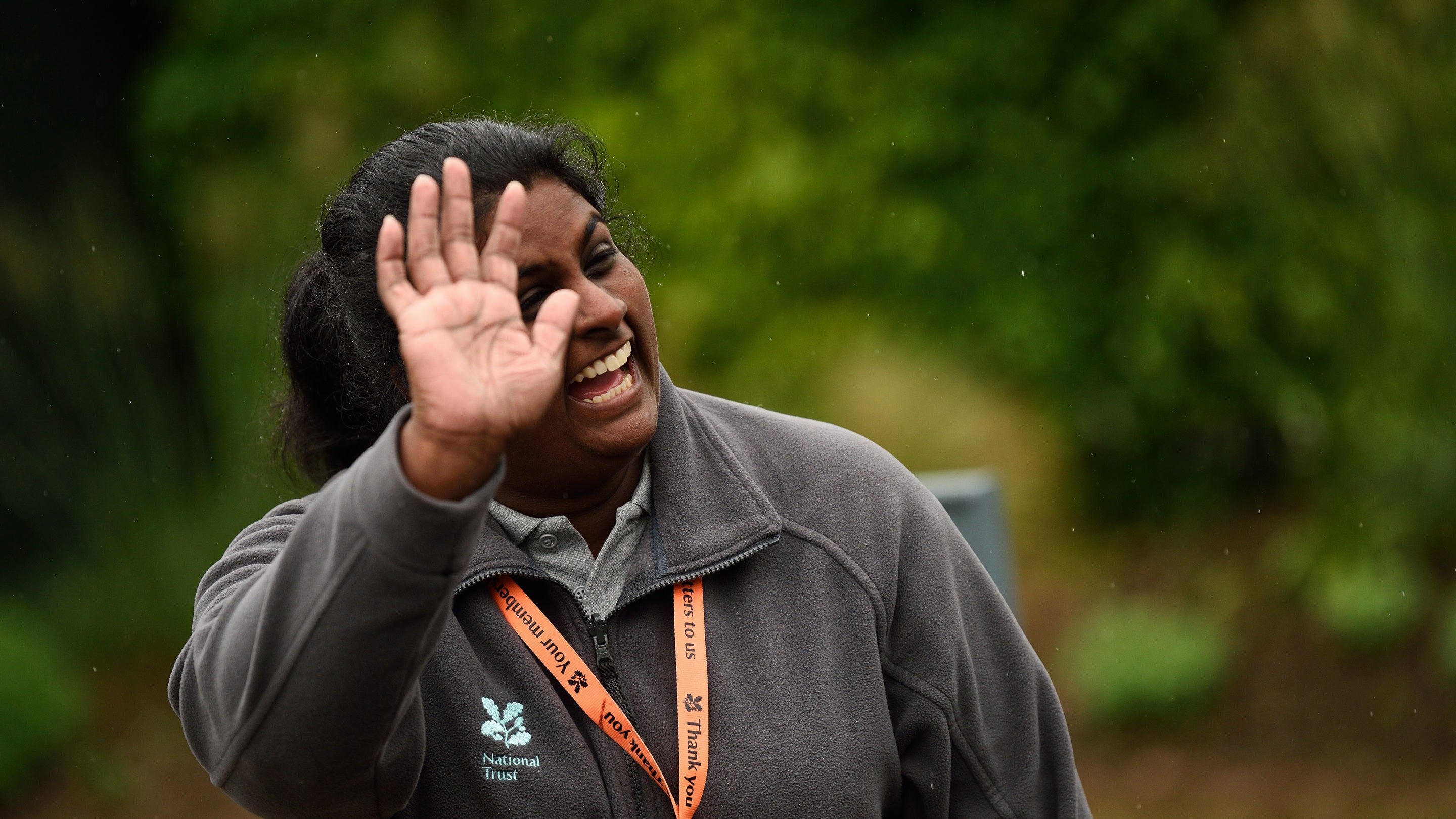 A volunteer waving and smiling at someone out of shot