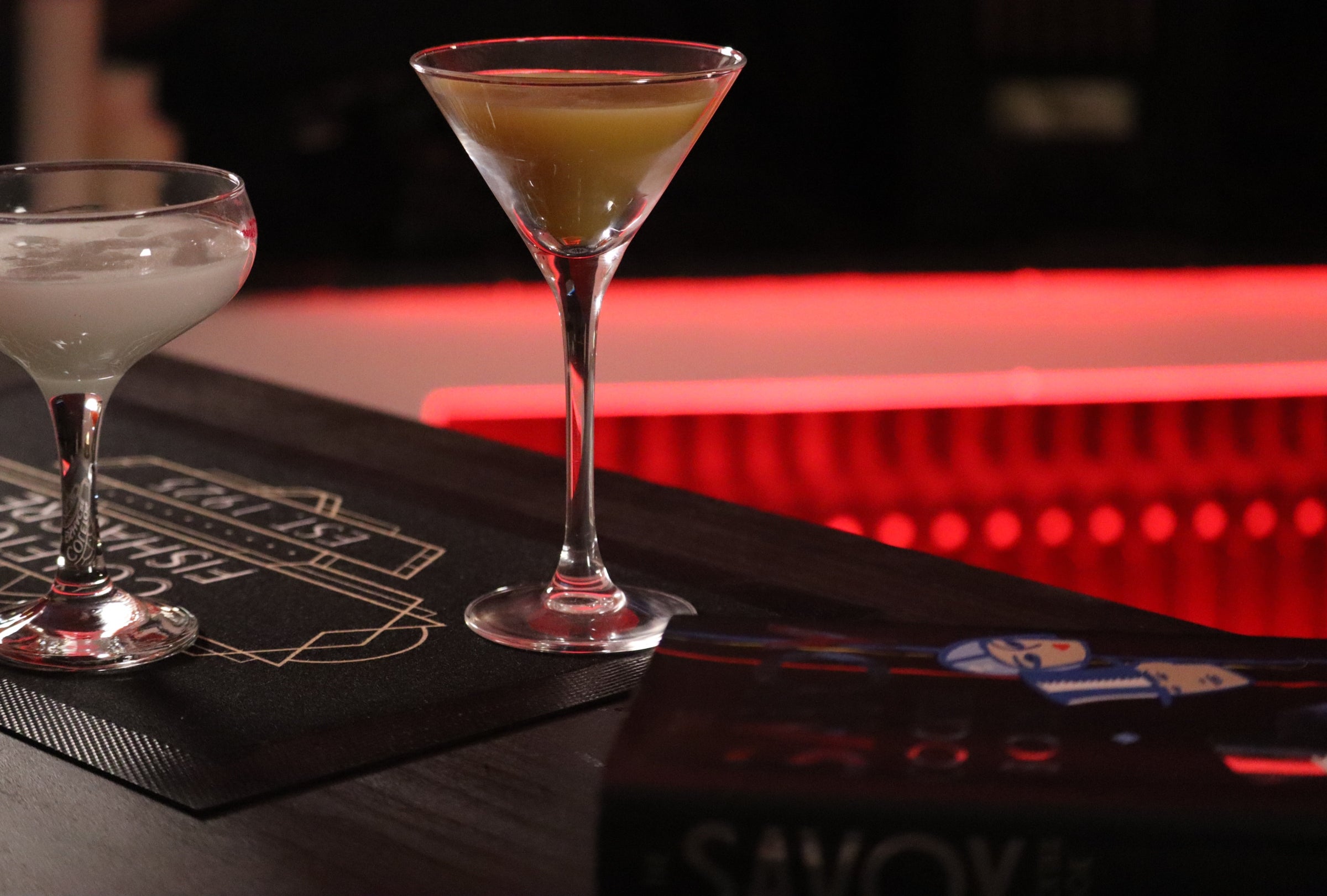Cocktail glasses and the Savoy Cocktail book on a bar in a pop-up speakeasy at Coleton Fishacre in Devon