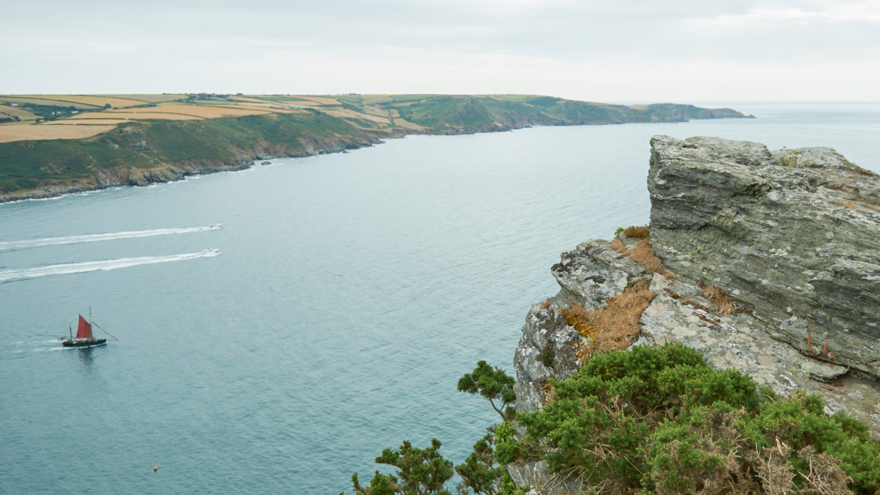 Boat sailing on the rugged coastline of Soar Mill Cove at East Soar, South Devon
