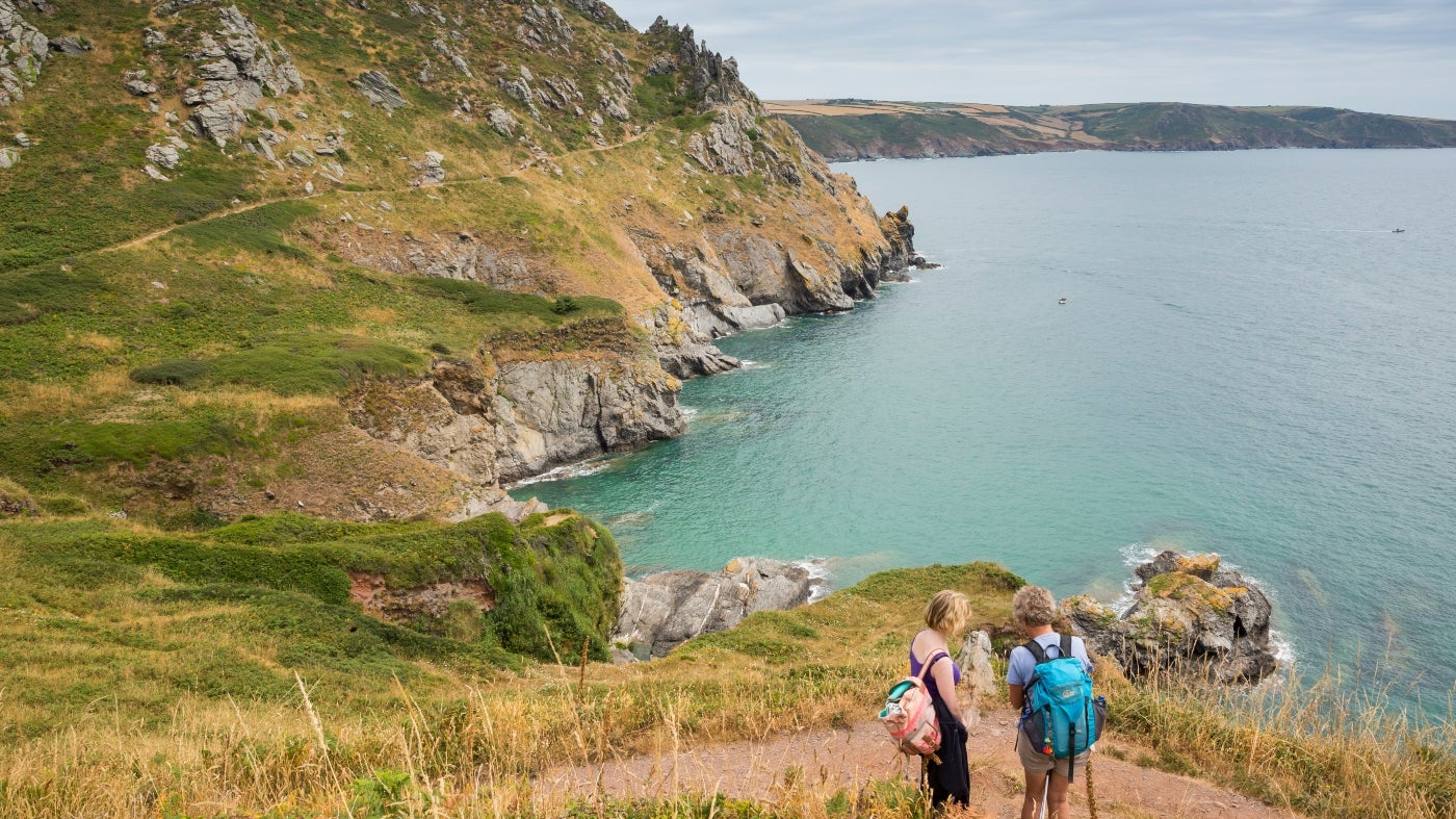 Two walkers stopping to look at the view across the water from the South West Coast Path