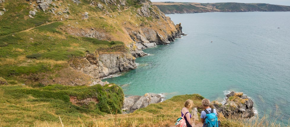 Two walkers stopping to look at the view across the water from the South West Coast Path