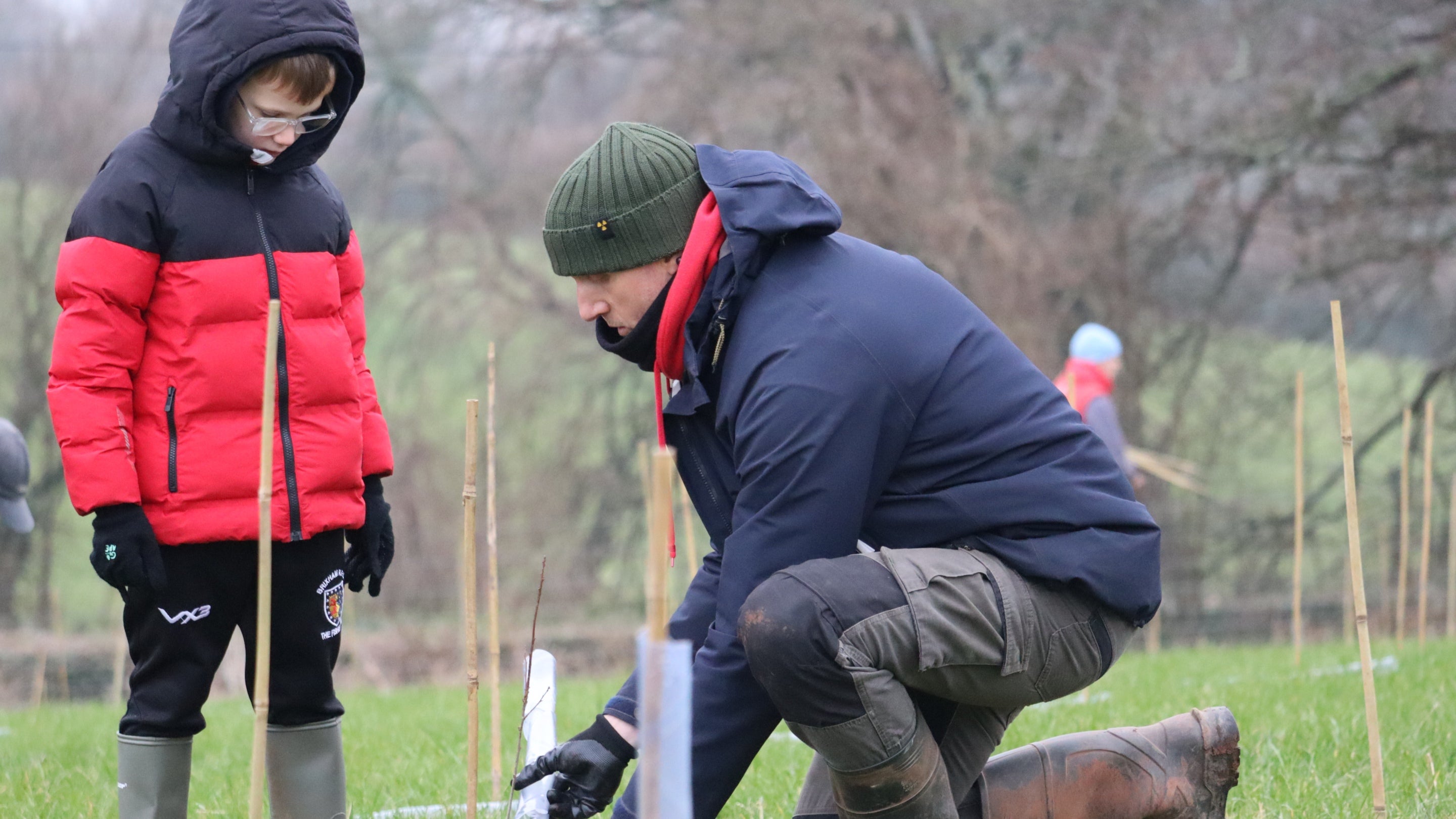 Child and adult planting a tree in a field
