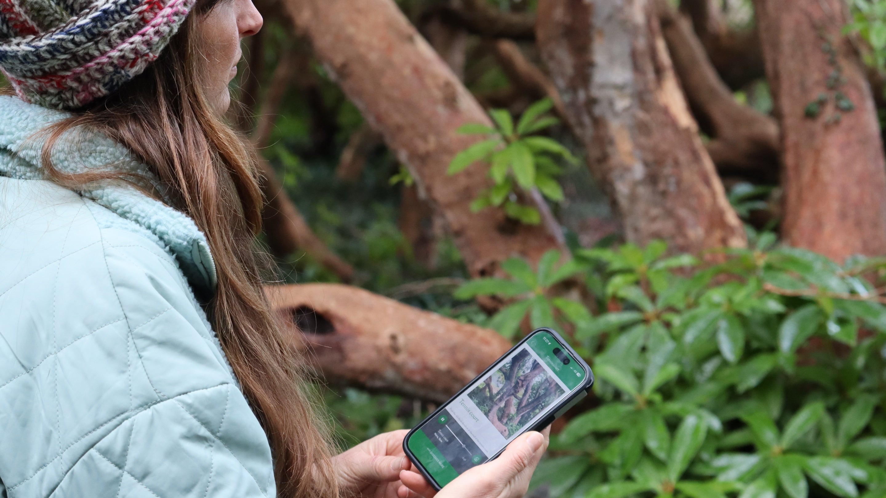 Visitor using the HistoryScapes app on a mobile phone in the garden at Greenway