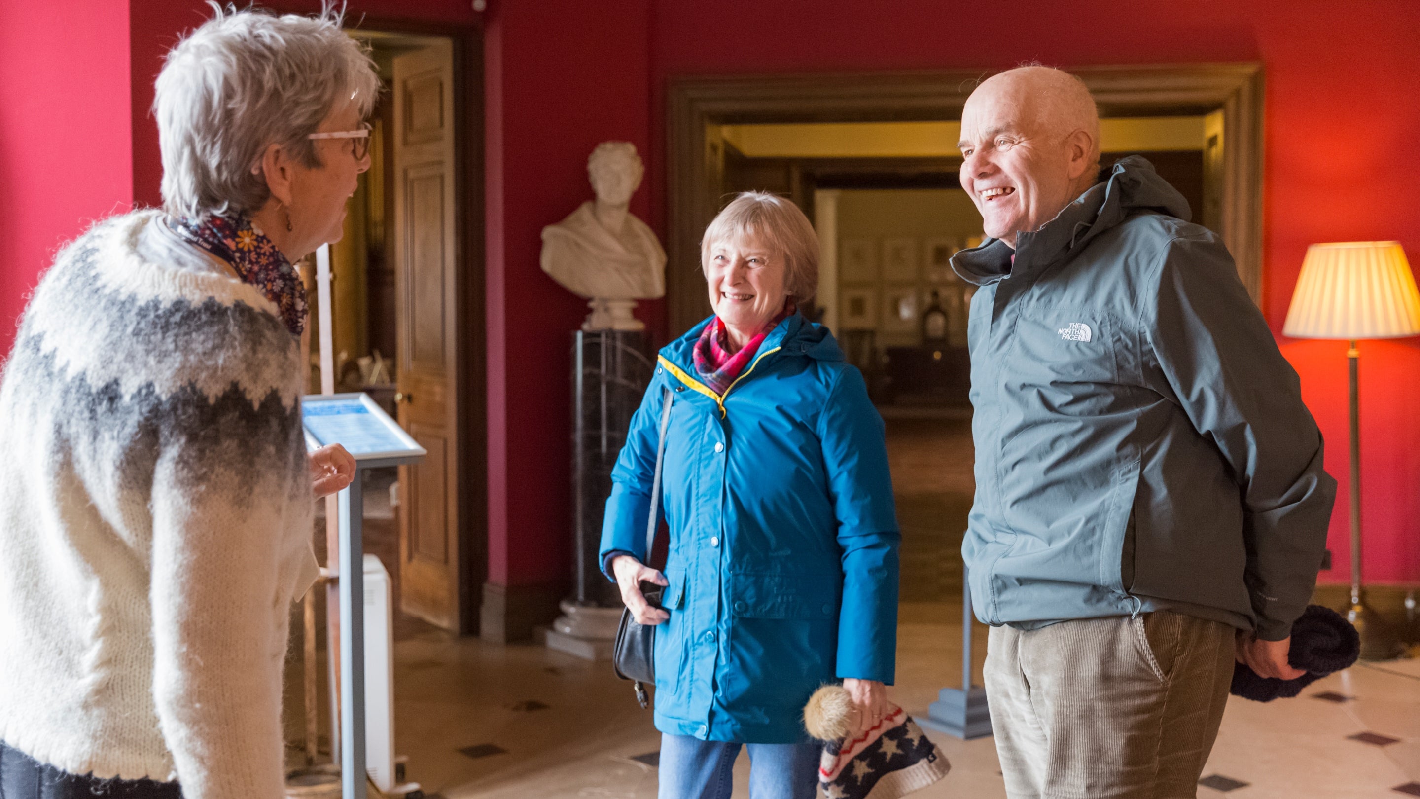 House room guide greeting two visitors in the entrance of Killerton House