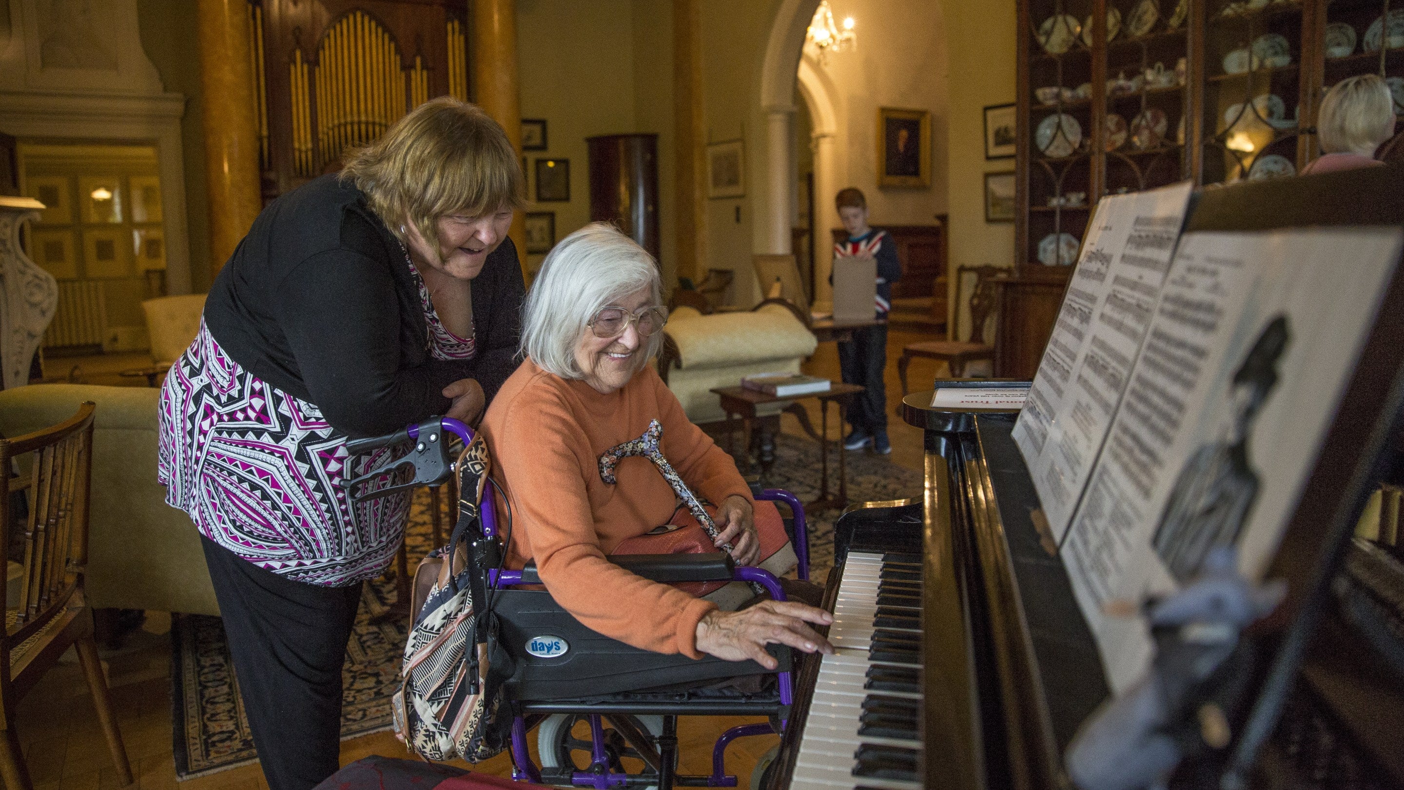 Visitor in wheelchair playing the piano at Killerton, Devon