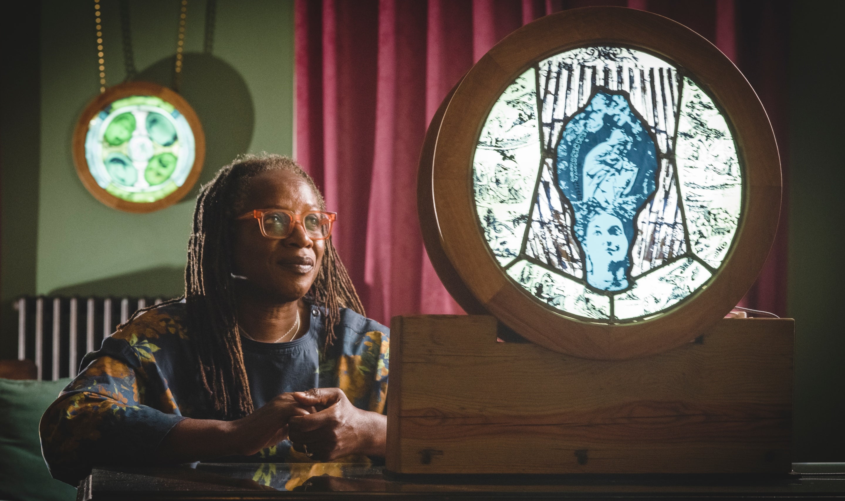Artist Patricia Dixon in the Study at Killerton with backlit roundels of stained-glass art