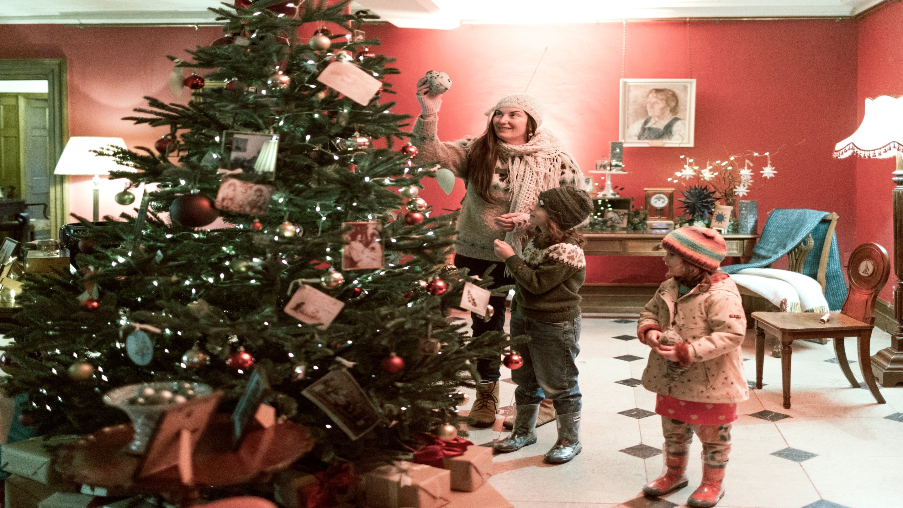 Visitors looking at a Christmas Tree in the entrance of Killerton House