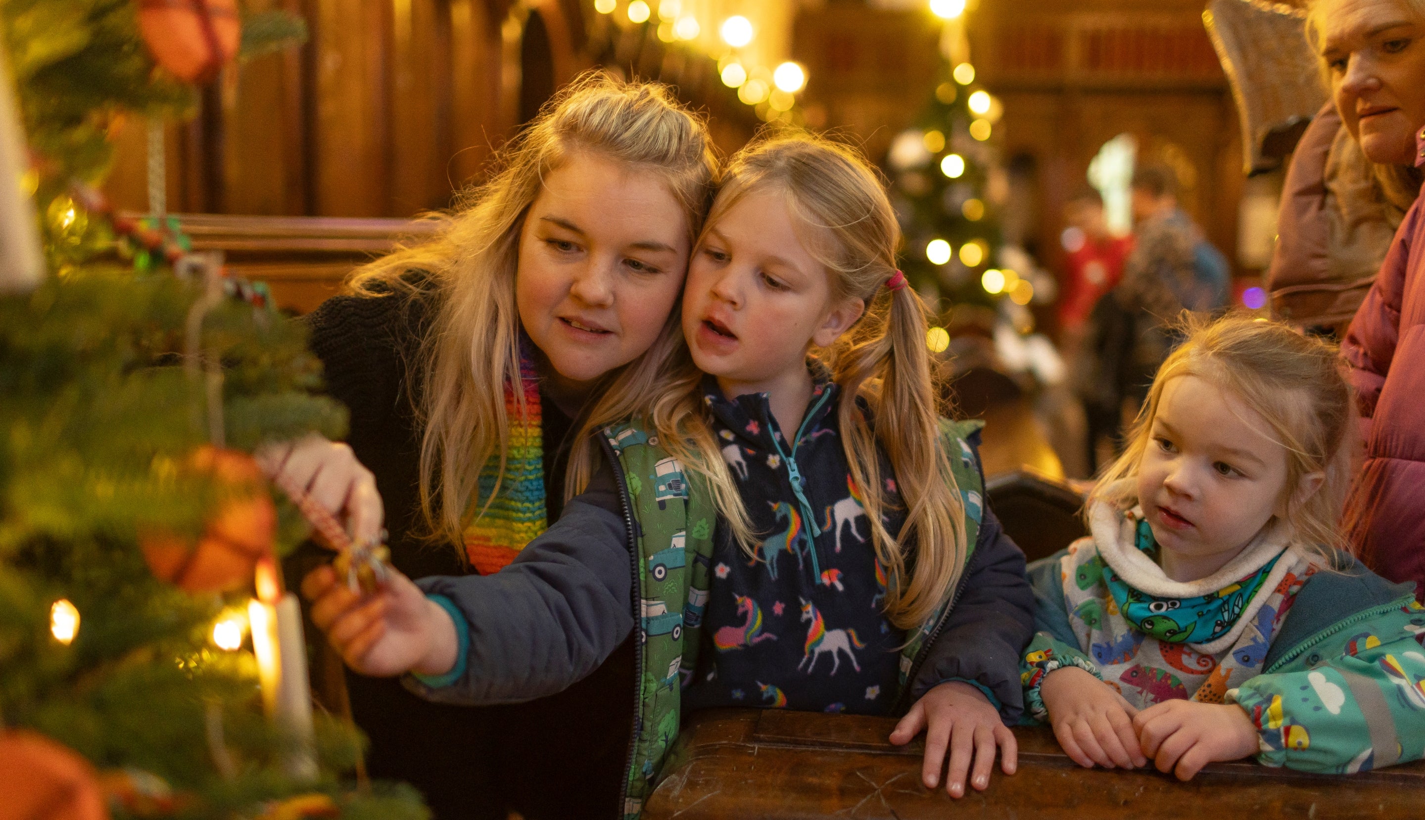 A family looking at the decorated community Christmas trees at Killerton