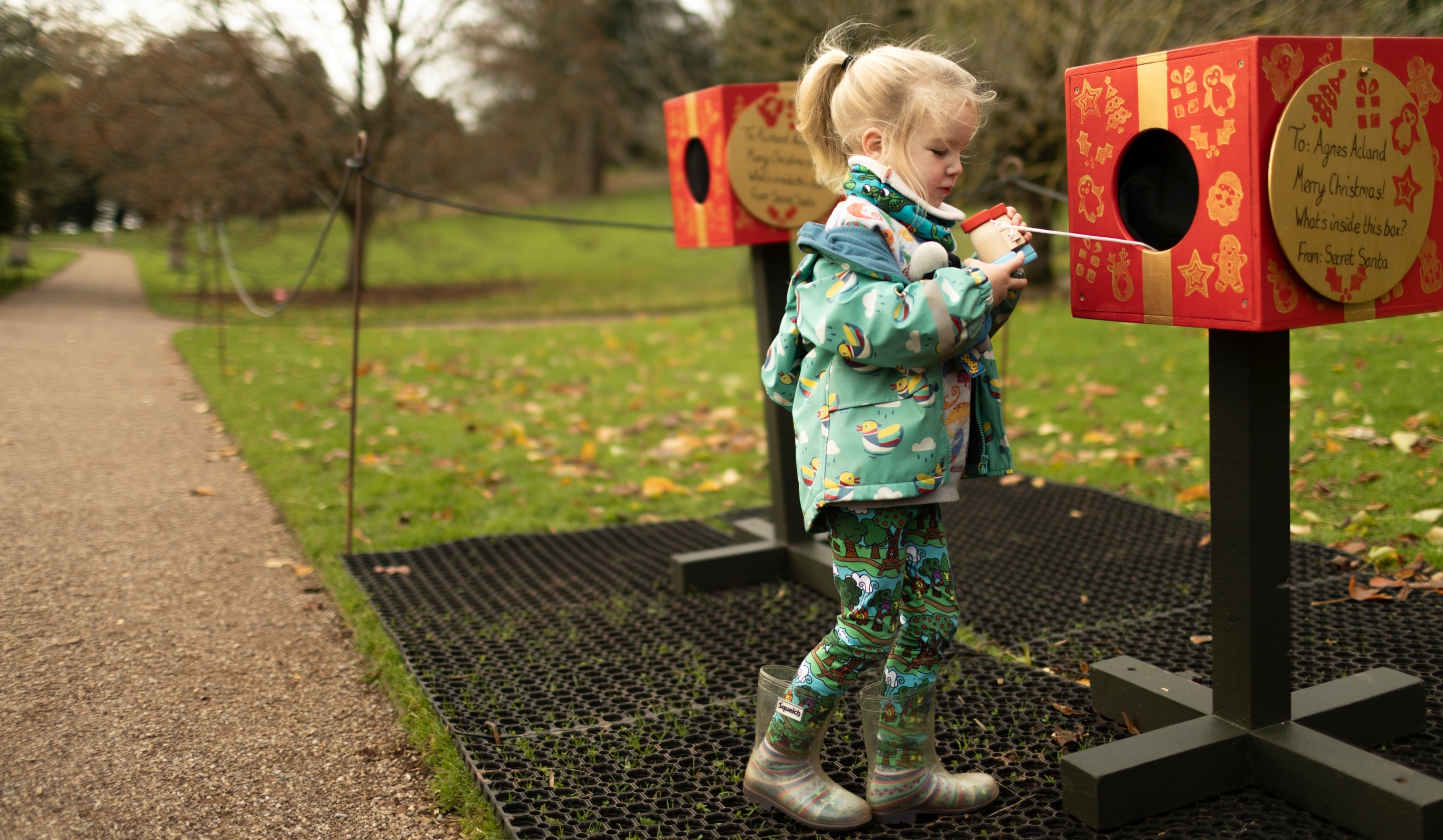 A child playing with peek boxes on an outdoor play trail at Killerton