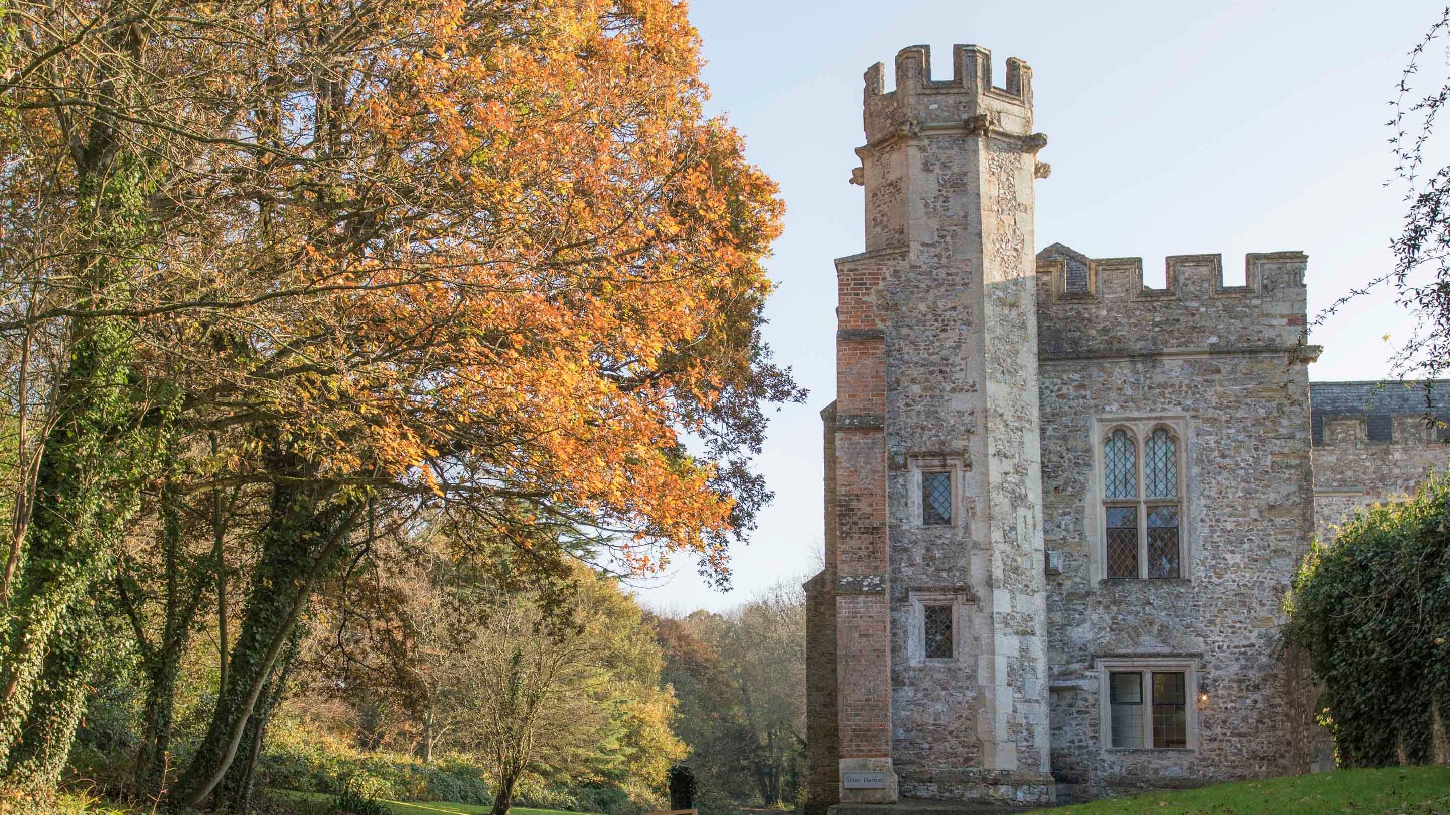 The hexagonal tower and house at Shute Barton surrounded by autumn leaves