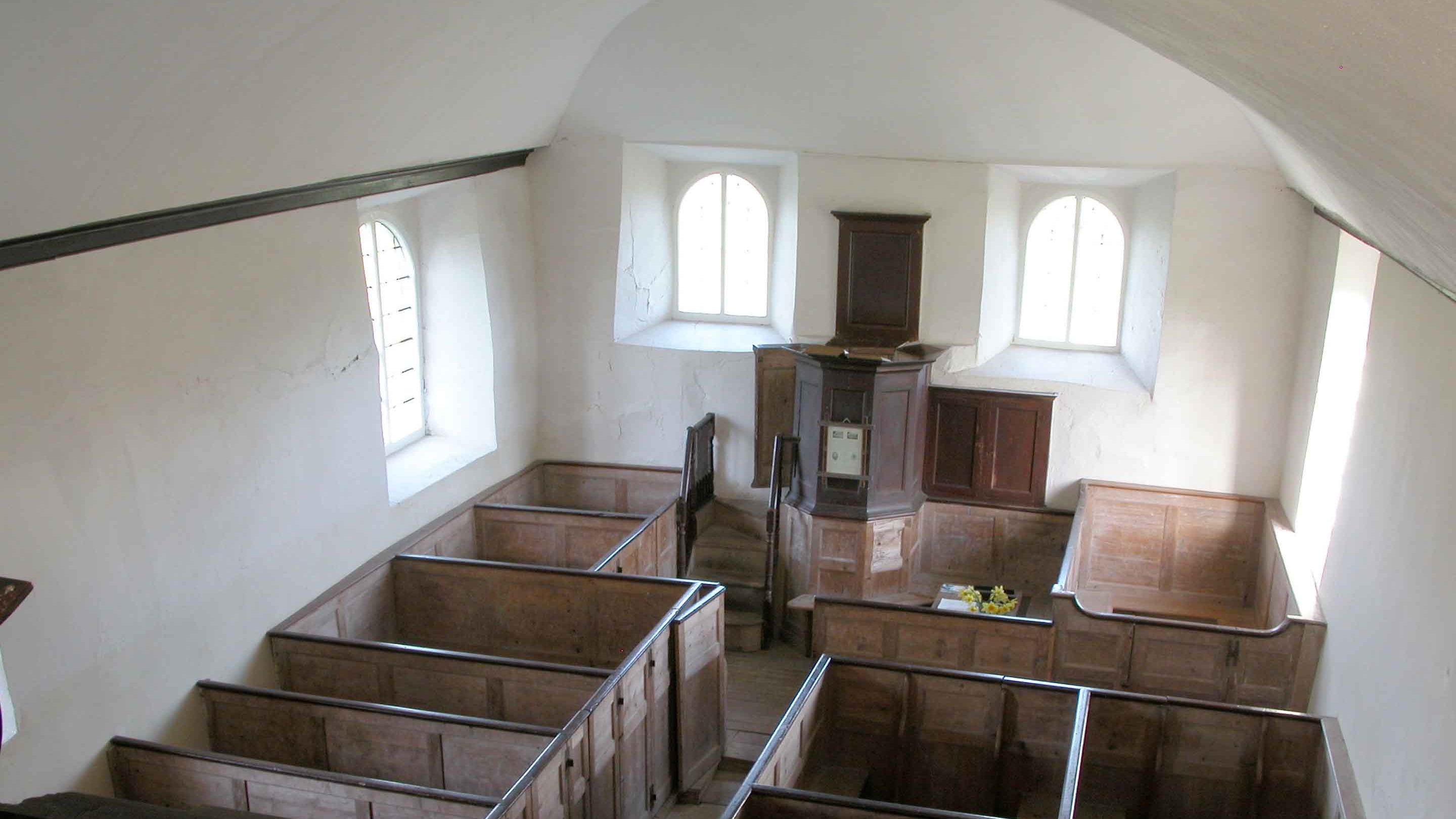 The inside of Loughwood Meeting House with white walls and wooden pews