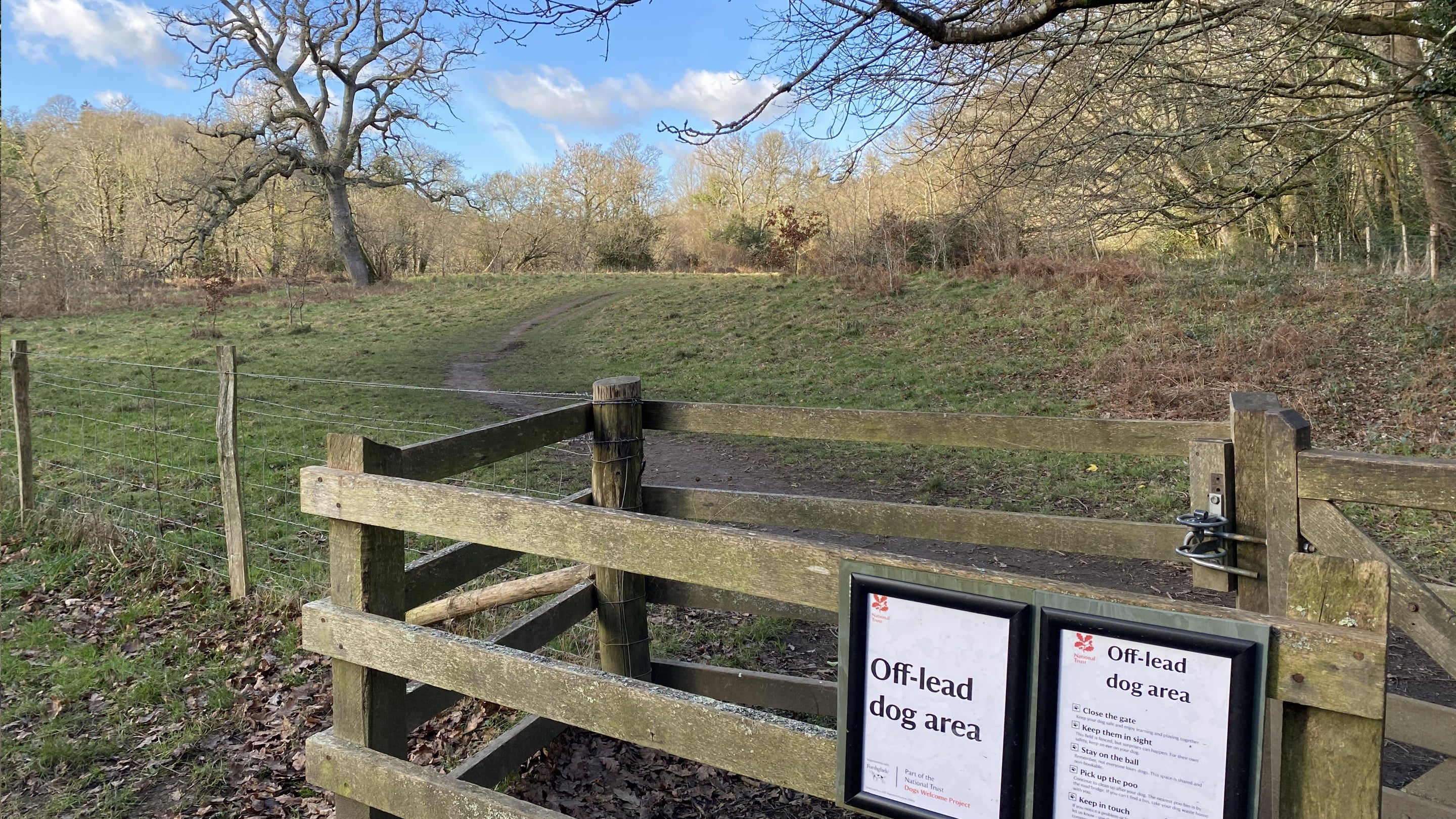 Gateway into fenced dog off-lead area with signs at Parke, Devon
