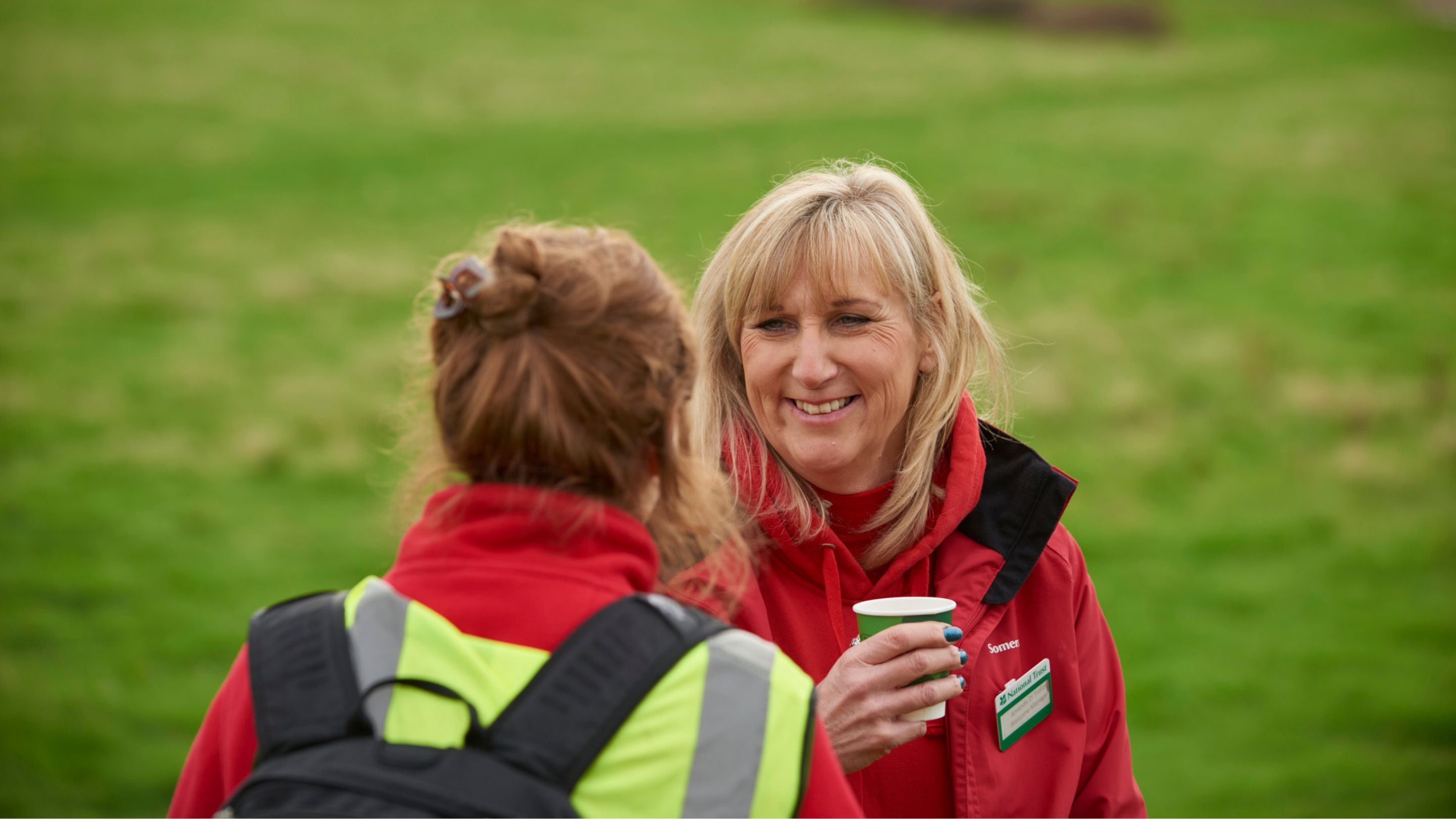 National Trust Rangers pictured smiling at each other at a community orchard tree planting event