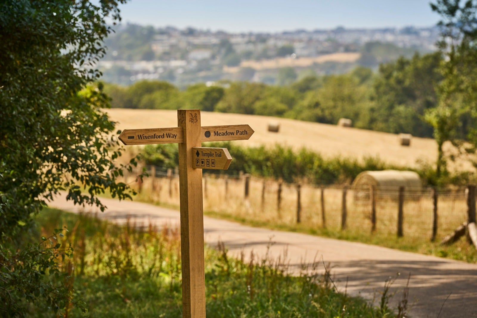 Image of new wayfinding post in front of field with hay bales showing Saltram's new walks on the east side of the estate