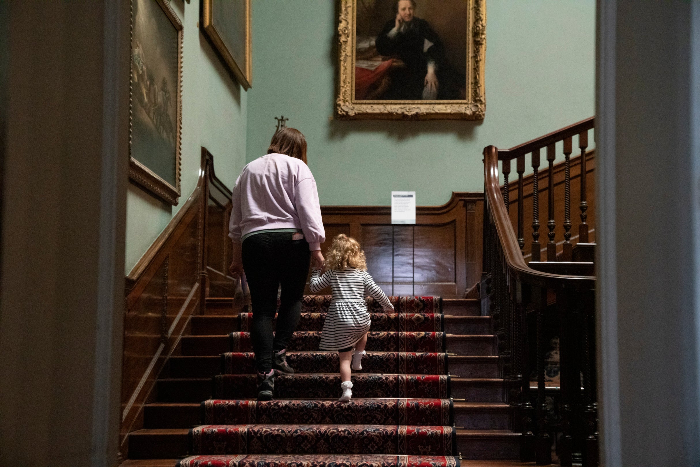 Mother and daughter explore Saltram's staircase hall looking at the paintings and lantern