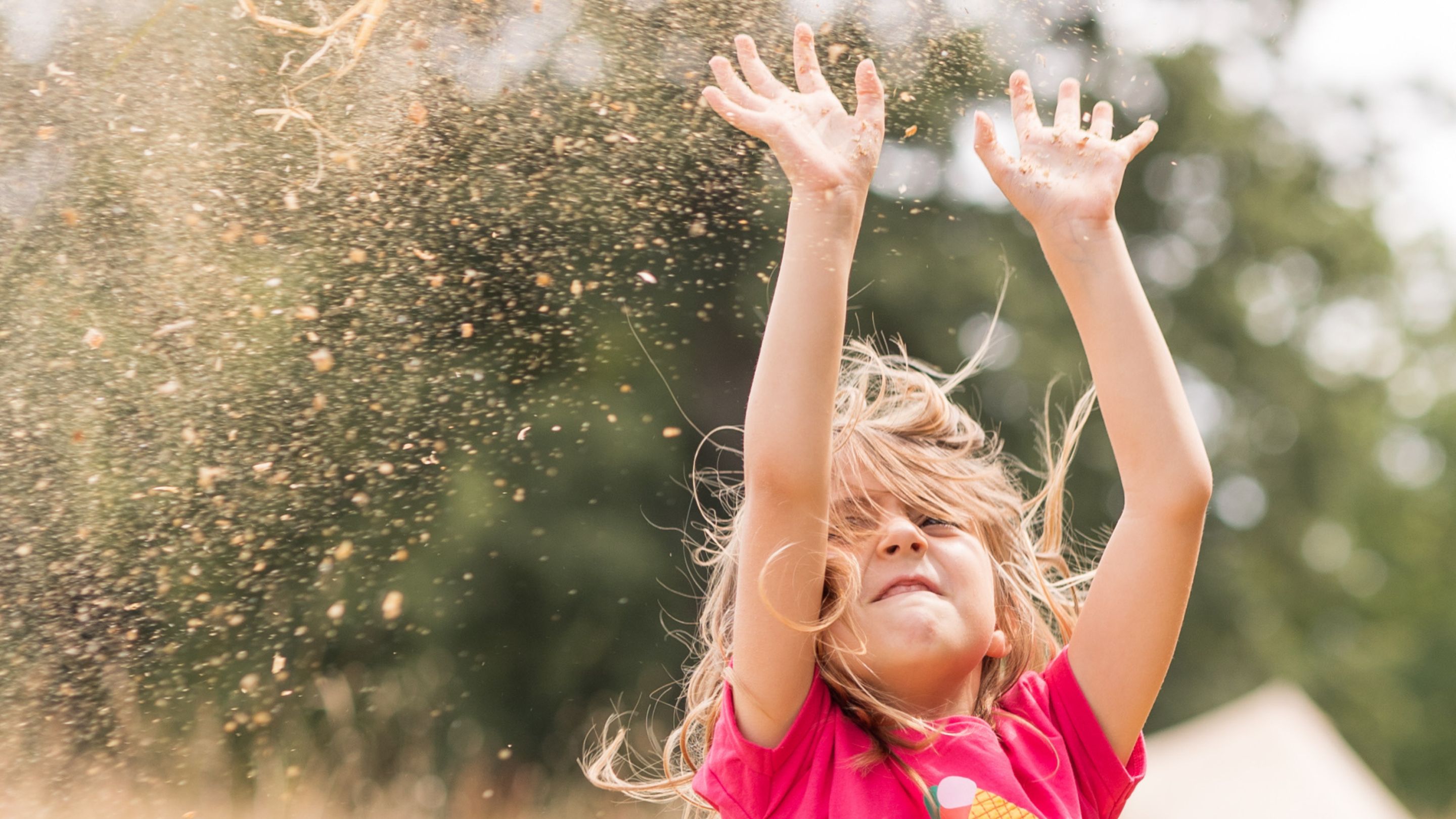 A girl throws sand in the air on a sensory walk
