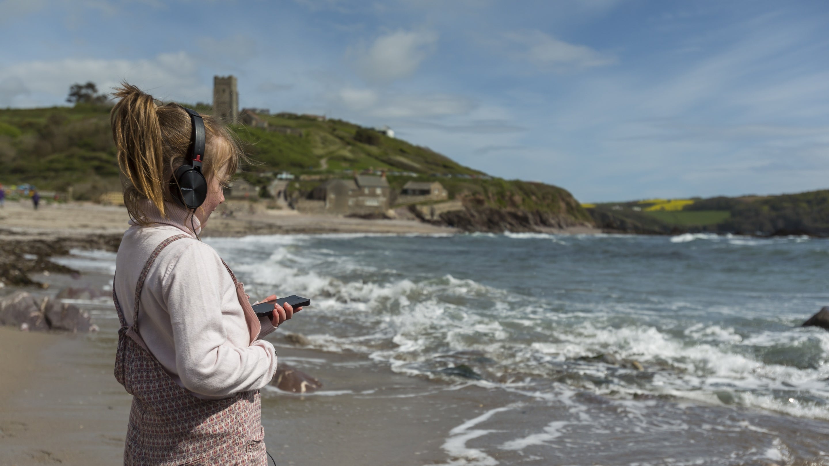 A child wearing headphones stares out to see while listening to audio.