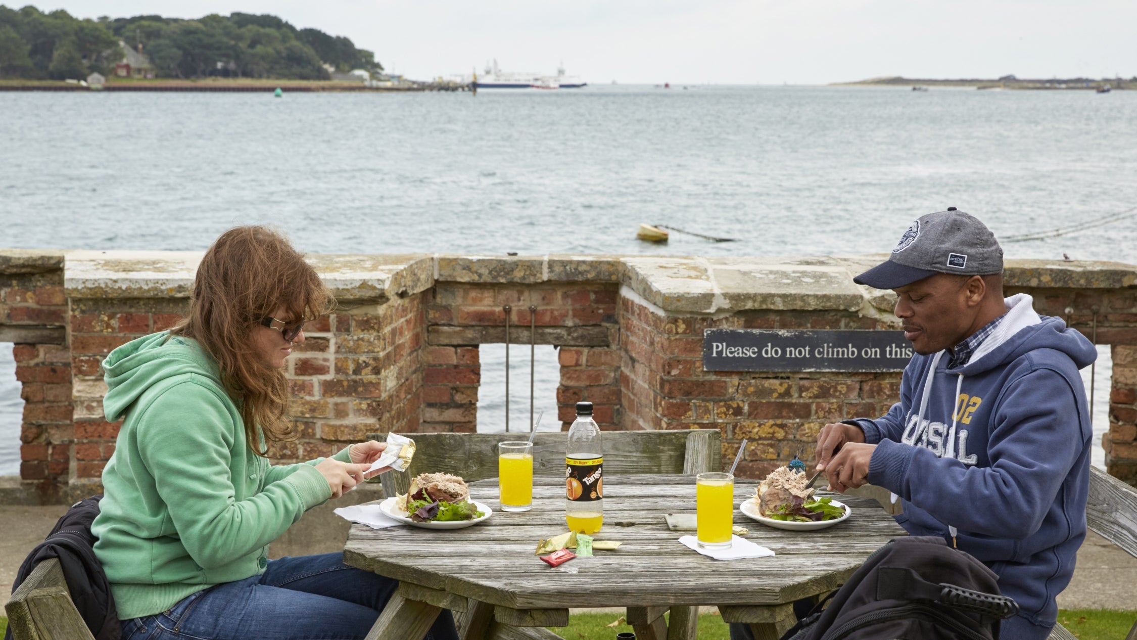 Couple eating at a picnic table with views over Poole Harbour in the background