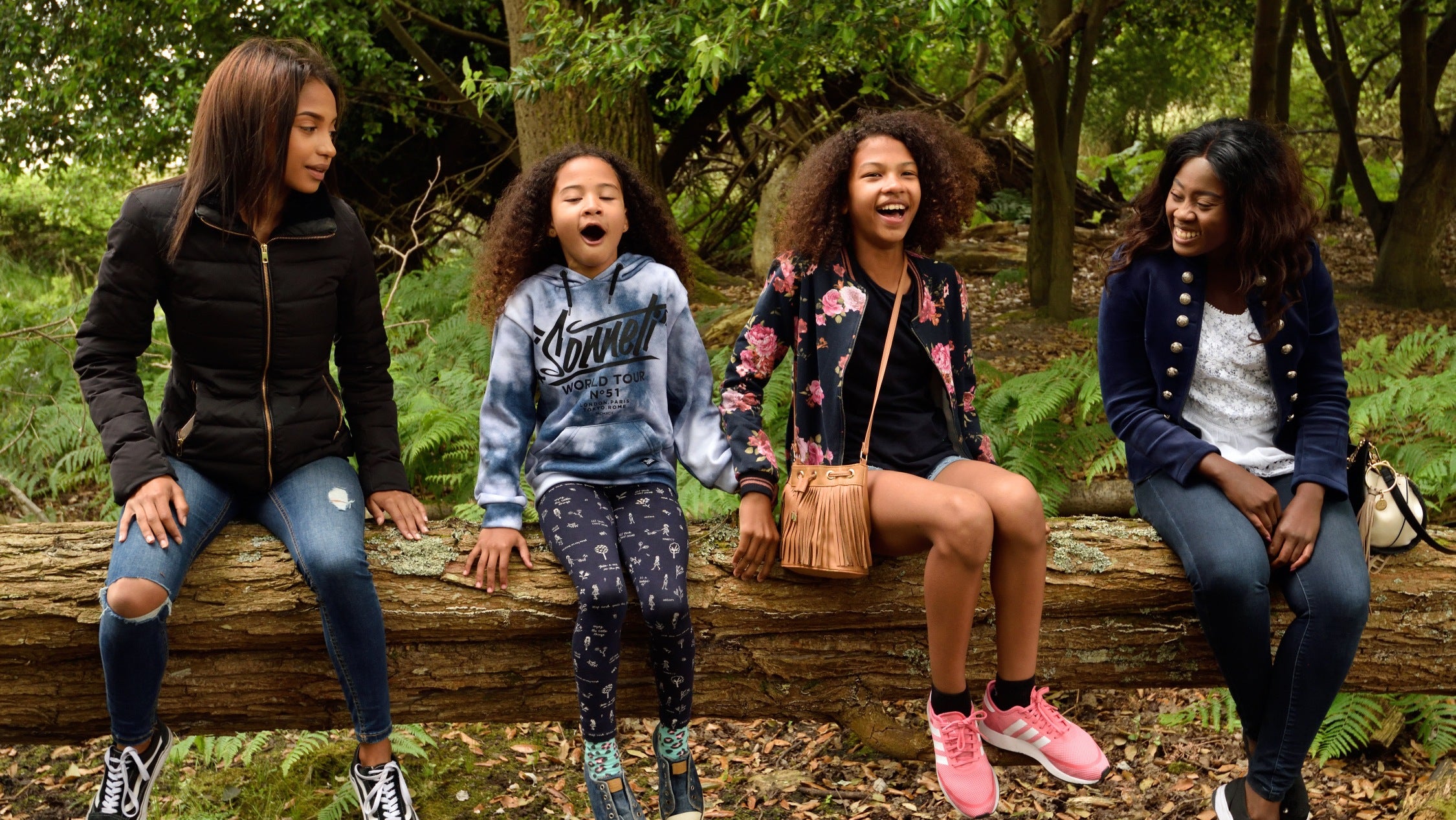 Family of four sitting on a log in the woods on Brownsea Island.