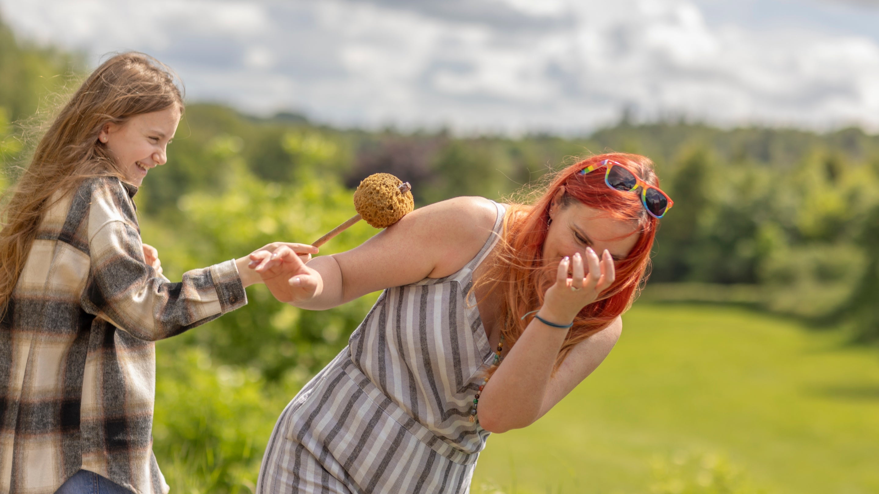 A daughter pointing a poostick at her mum making her cover her mouth.