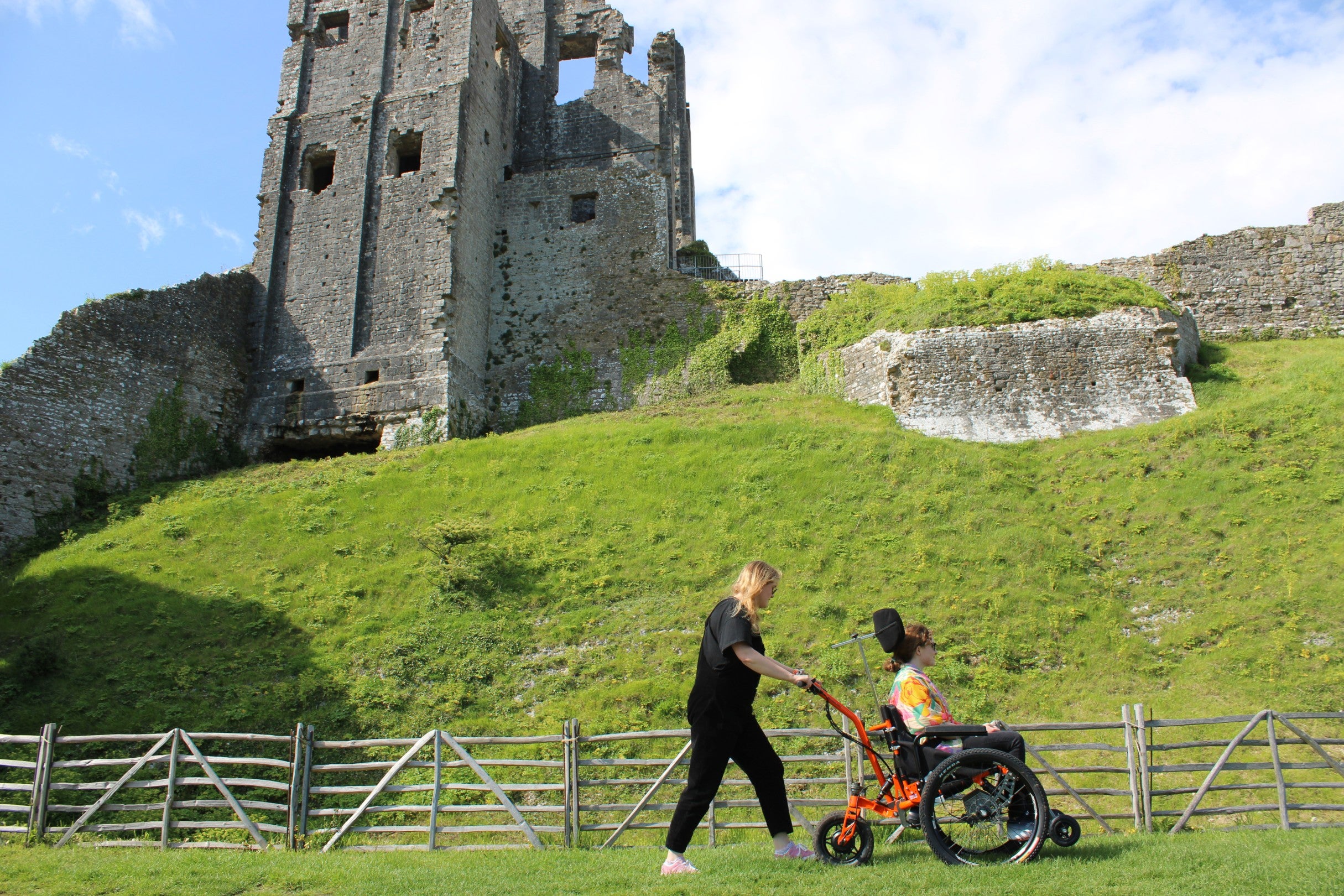 Visitors exploring Corfe Castle in summer using all-terrain electric wheelchair.