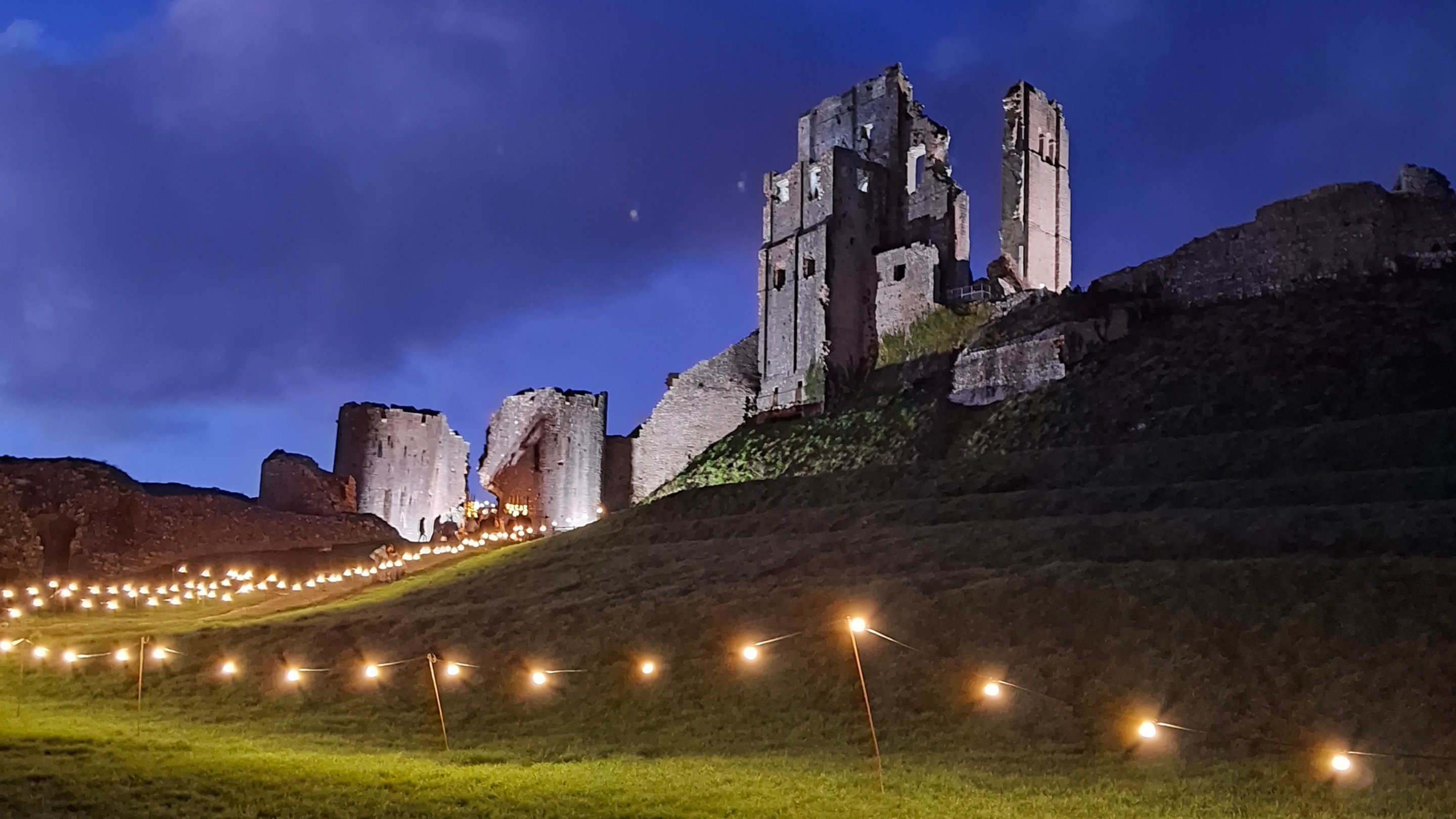 Corfe Castle lit at night with festoon lights around the edge