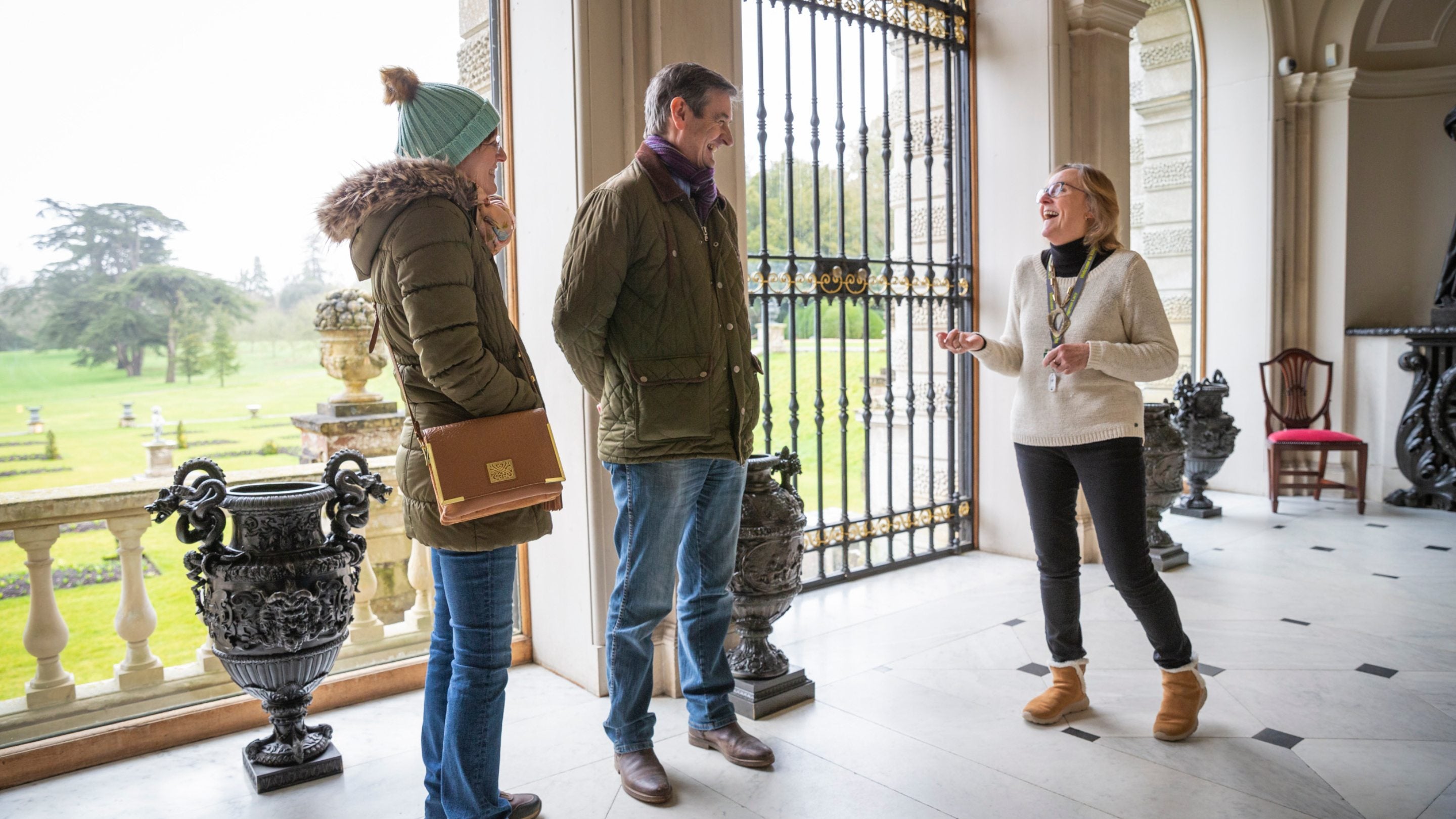 Three people in a light-filled space, with big windows overlooking a garden
