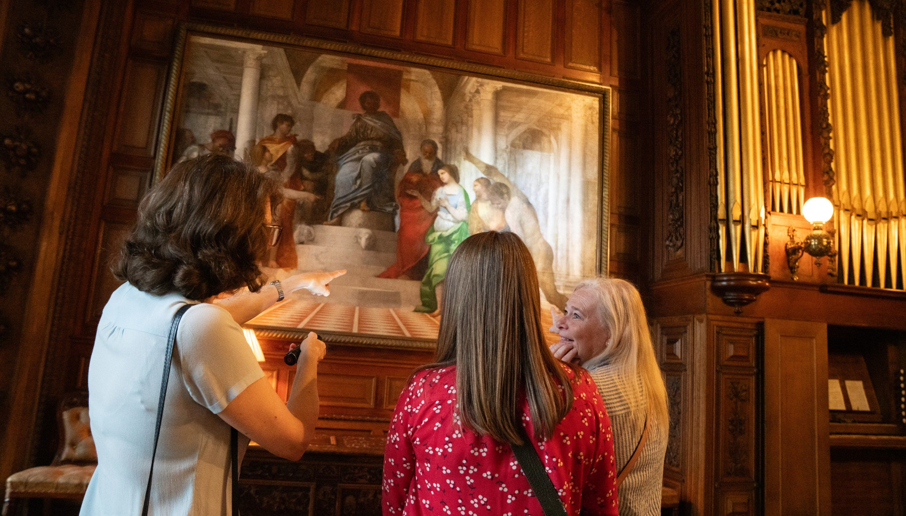 Three women in front of a Renaissance masterpiece depicting the judgement of Solomon