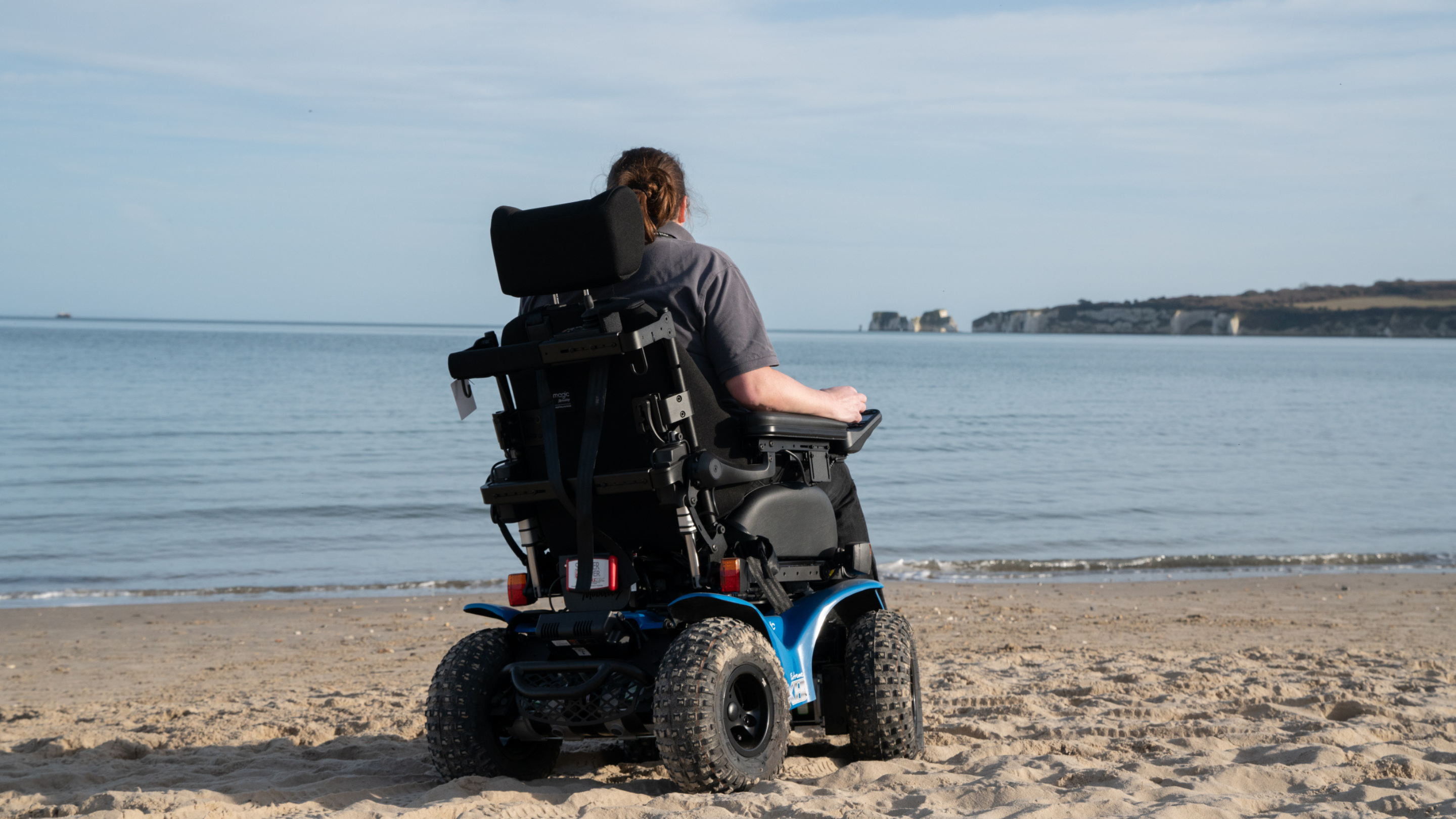 Image showing electric wheelchair and user on the beach at Studland Bay with Old Harry Rocks in the background