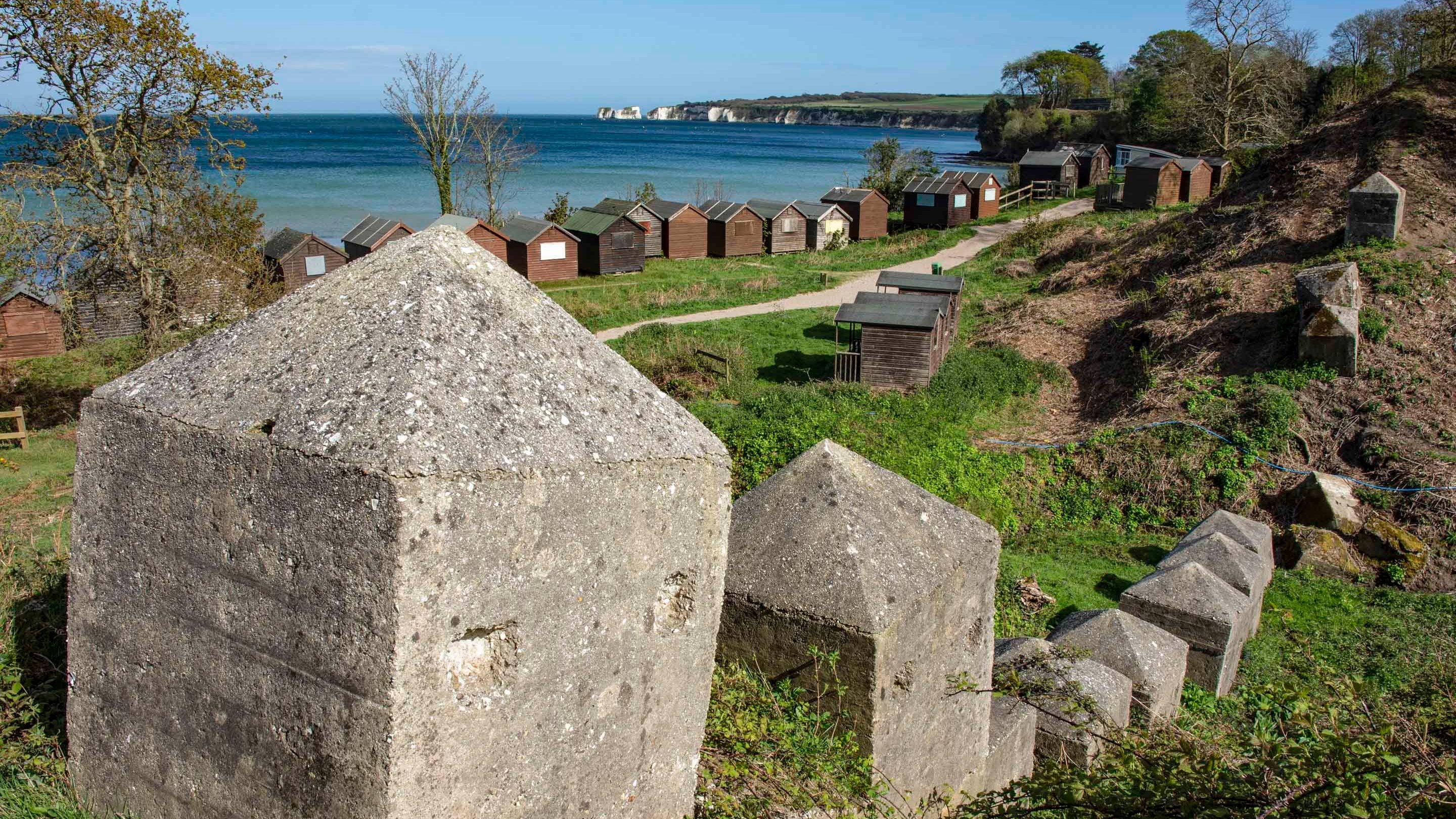 A close up of Second World War defences with beach huts in the background at Middle Beach, Studland Bay, Dorset